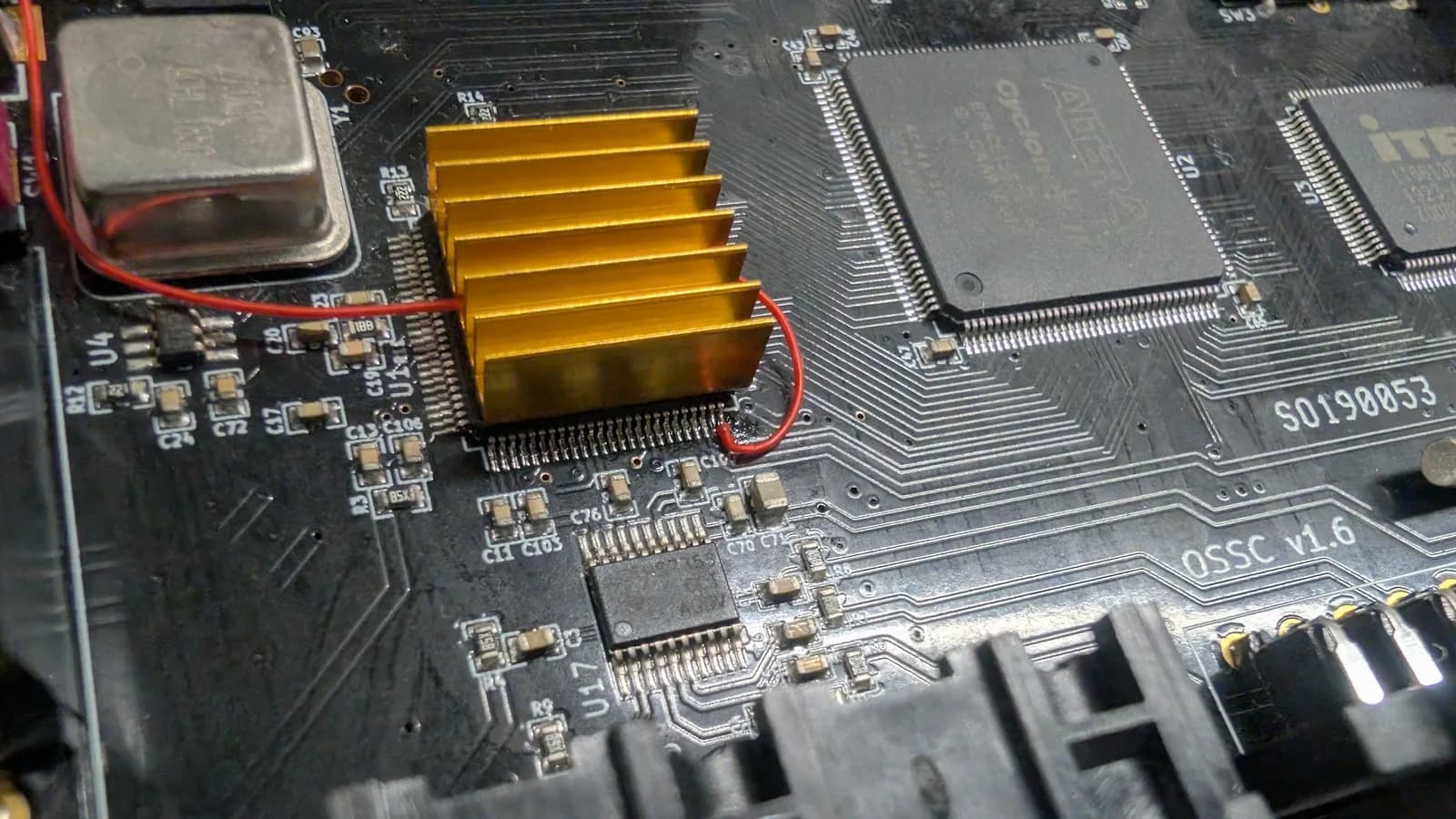 Gold heatsink on the OSSC classic PCB, with a single red kynar wire soldered to a pin of the IC beneath the heatsink (the firmware-enable mod).