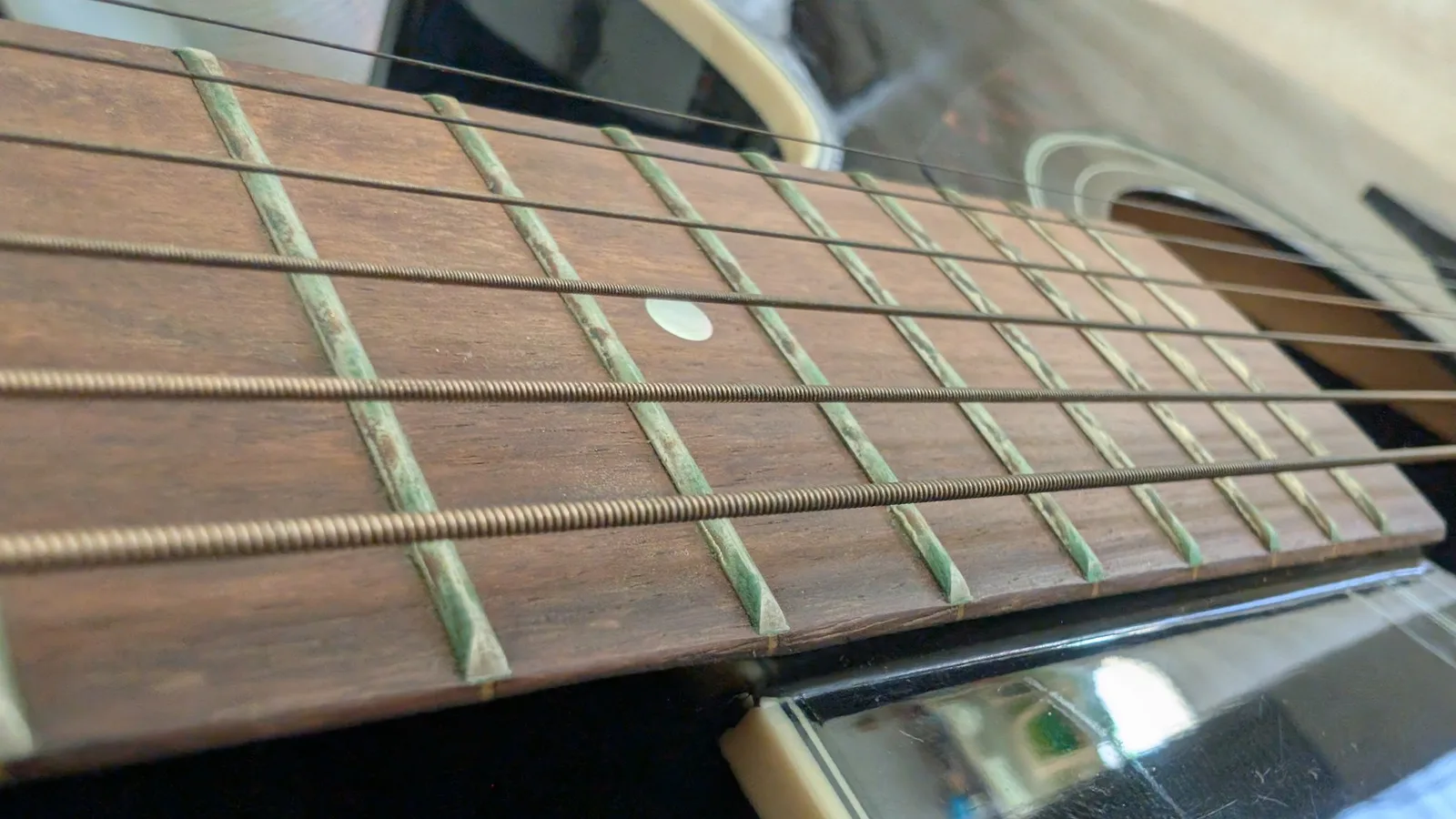 Yamaha FX370C fretboard close-up showing cleaned frets with inlays and newly installed strings after maintenance.