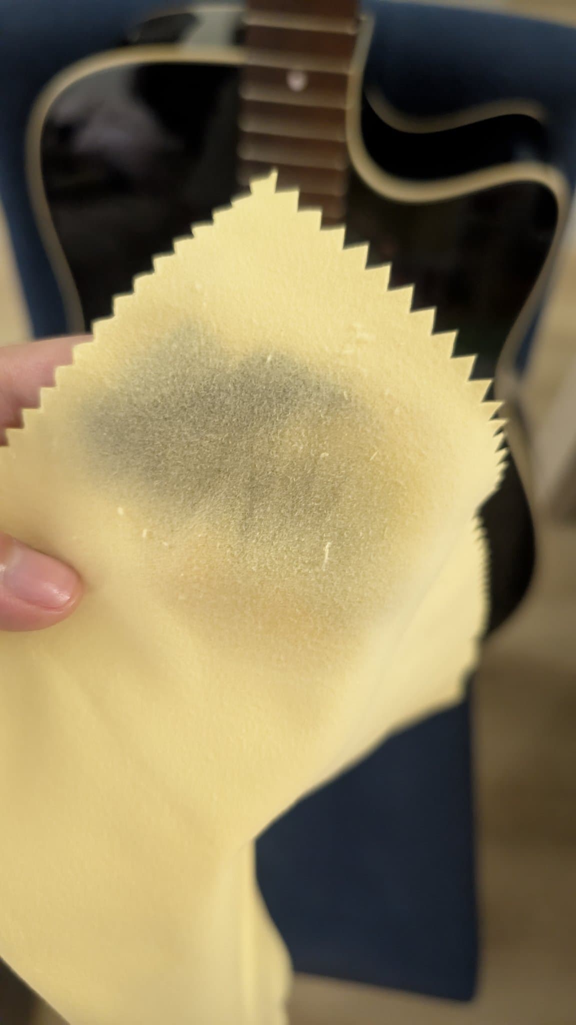 Hands applying lemon oil to Yamaha FX370C fretboard during cleaning and maintenance, showing treated rosewood surface.
