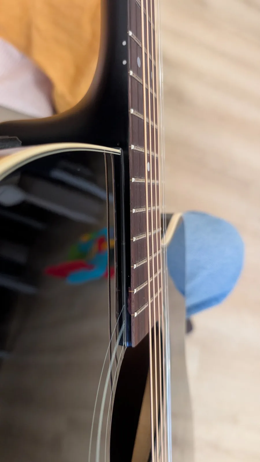 Close-up of Yamaha FX370C fretboard and strings showing fret cleaning work completed, with blue pick visible.