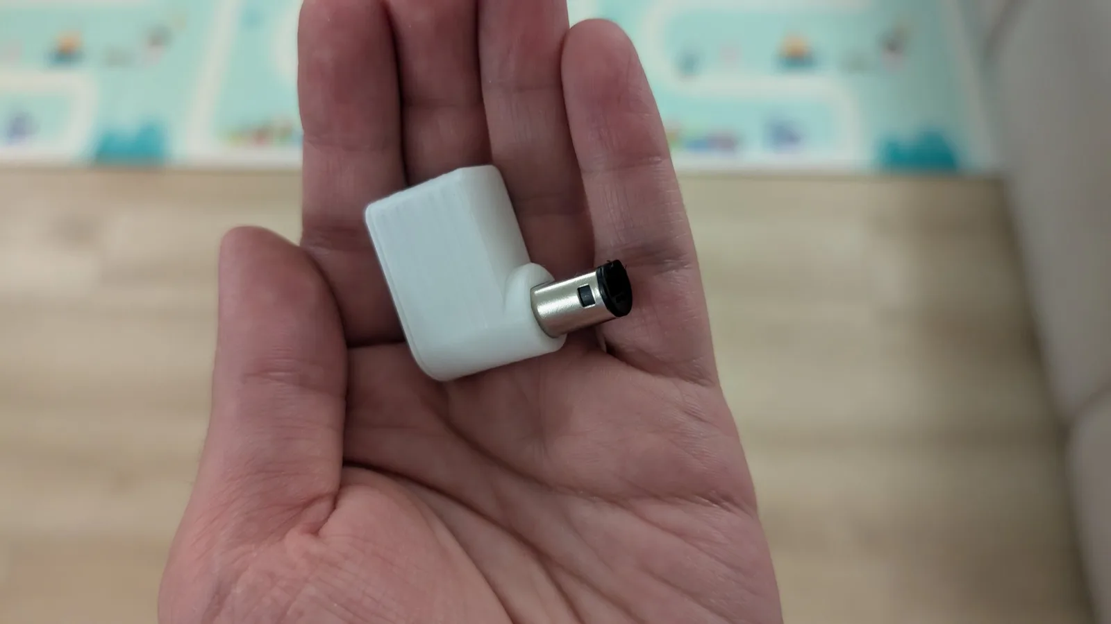 White 3D-printed WavePhoenix receiver held in an open palm, a metal GameCube controller plug protruding from one end; snap-fit shell.