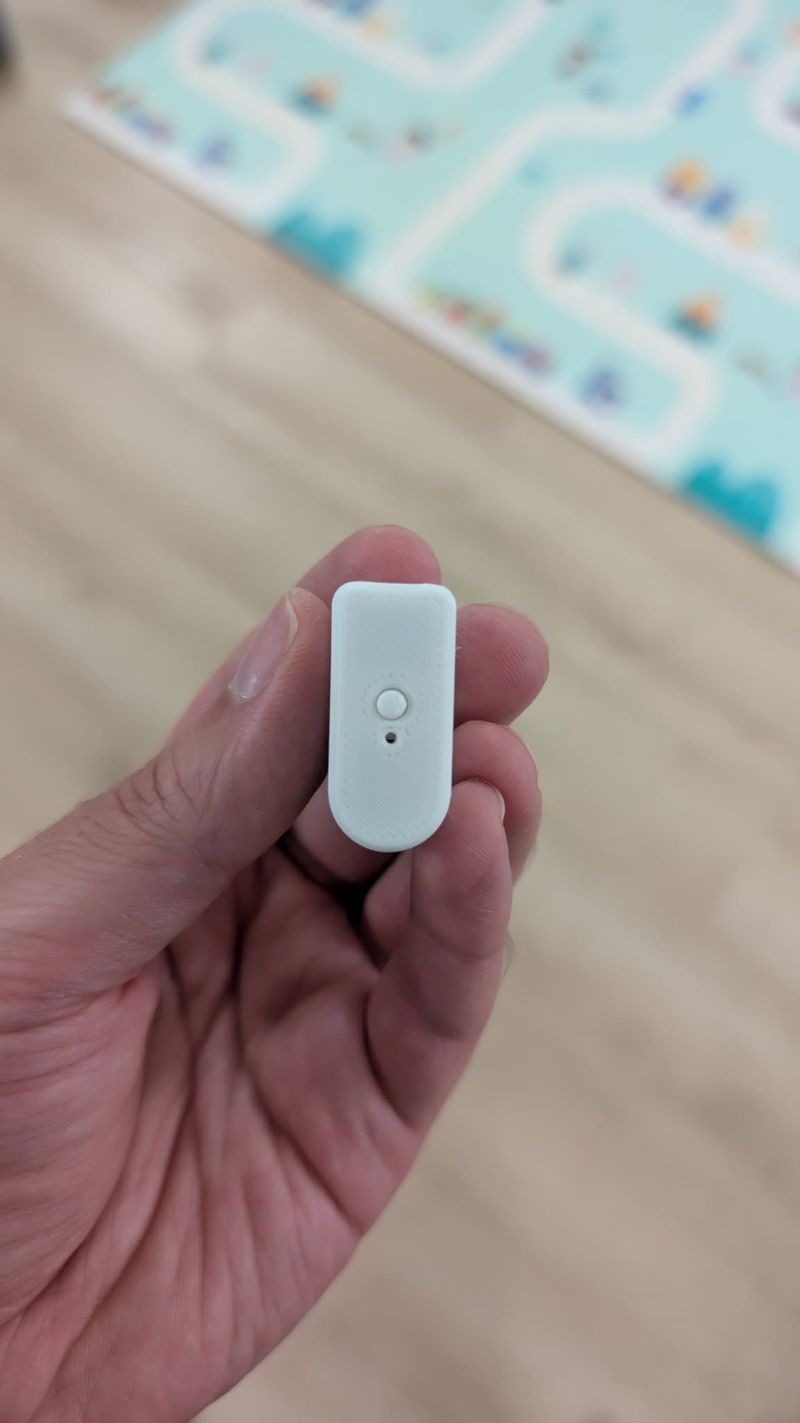 White WavePhoenix receiver shell held in hand, showing power button and LED indicator, with GameCube controller visible in blurred background.