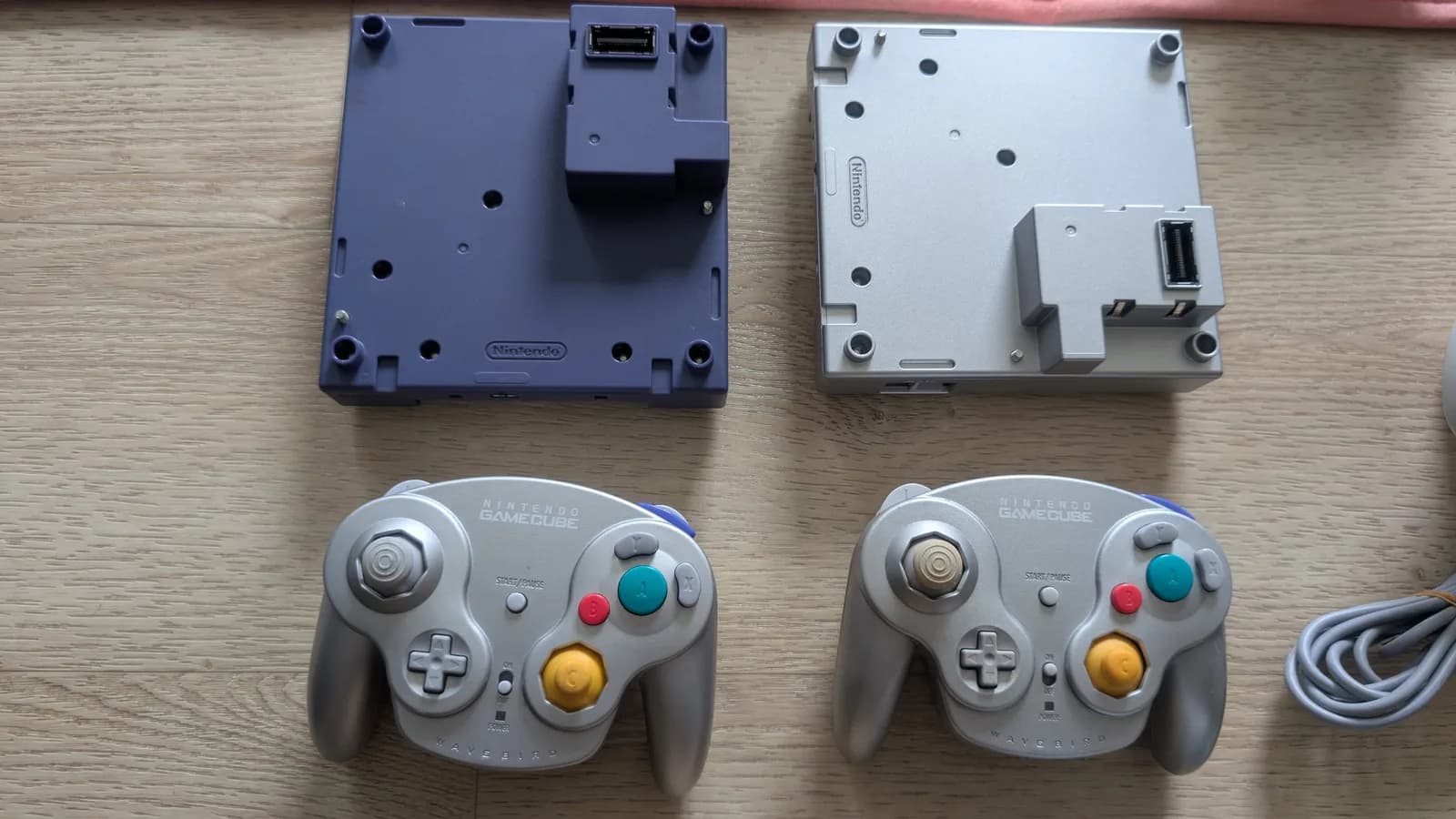 Two Game Boy Players (indigo and silver), the add-on that mounts under a GameCube, with two silver GameCube controllers, during the fleet restoration.