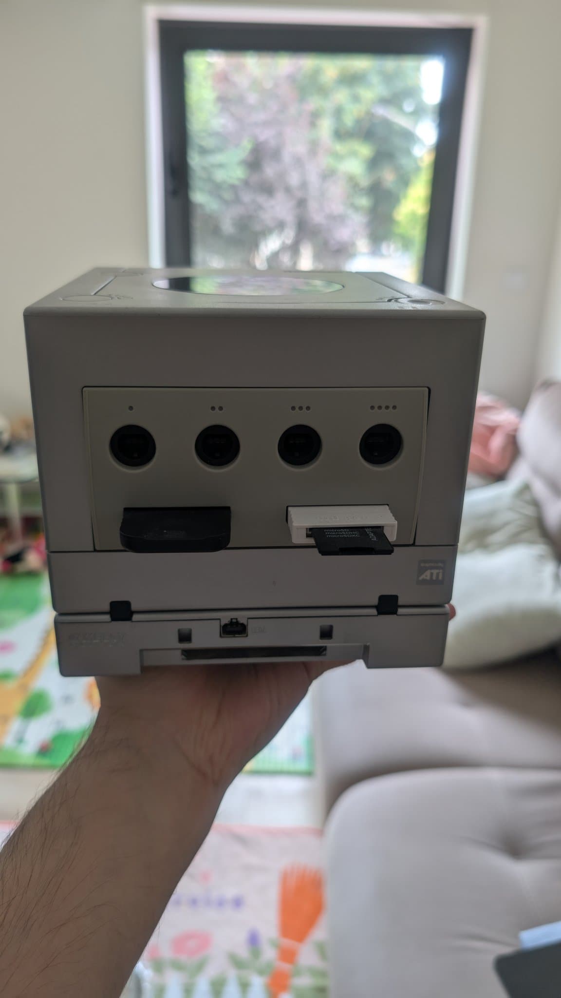 Silver GameCube held in hand showing front panel with four controller ports and memory card slot after retrobrighting restoration.