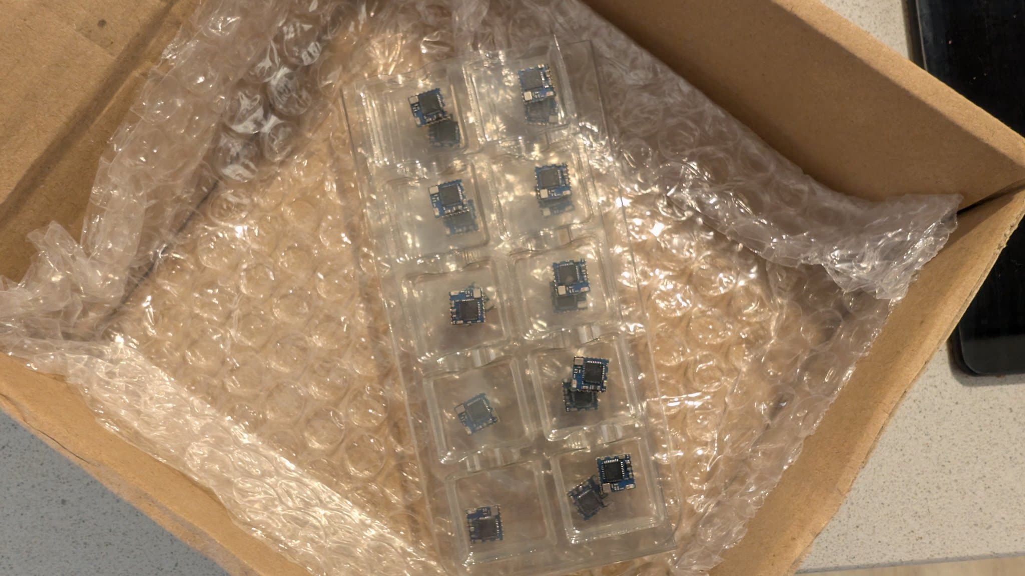 WavePhoenix PCBs in bubble wrap showing soldered components and blue integrated circuits during hot air reflow assembly work.