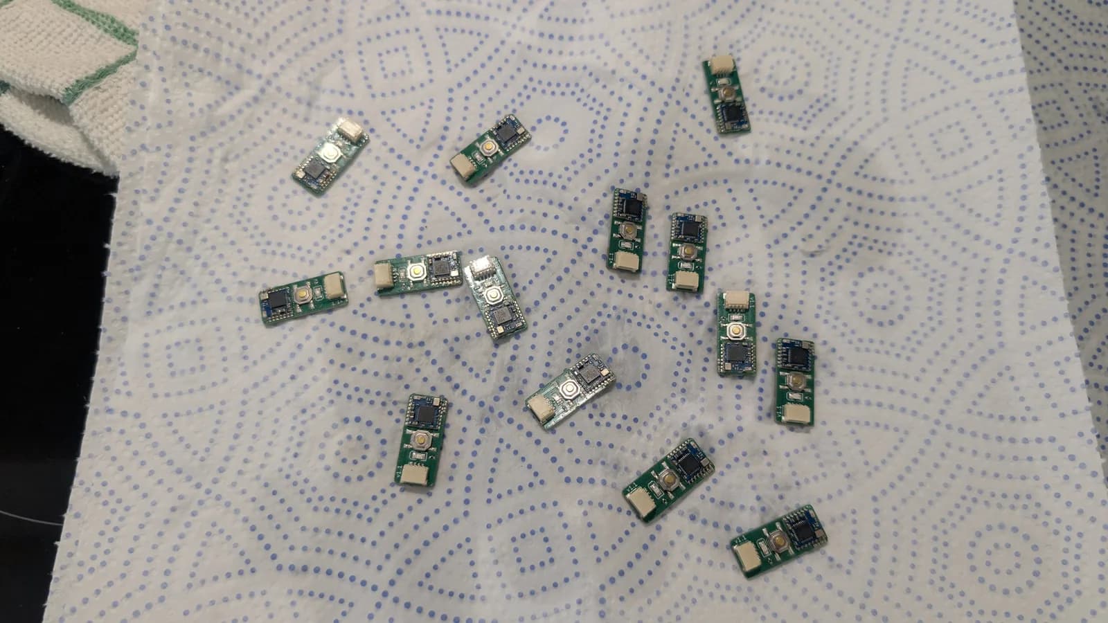 Multiple cleaned WavePhoenix receiver boards laid out on a blue-dotted paper towel to dry before testing.