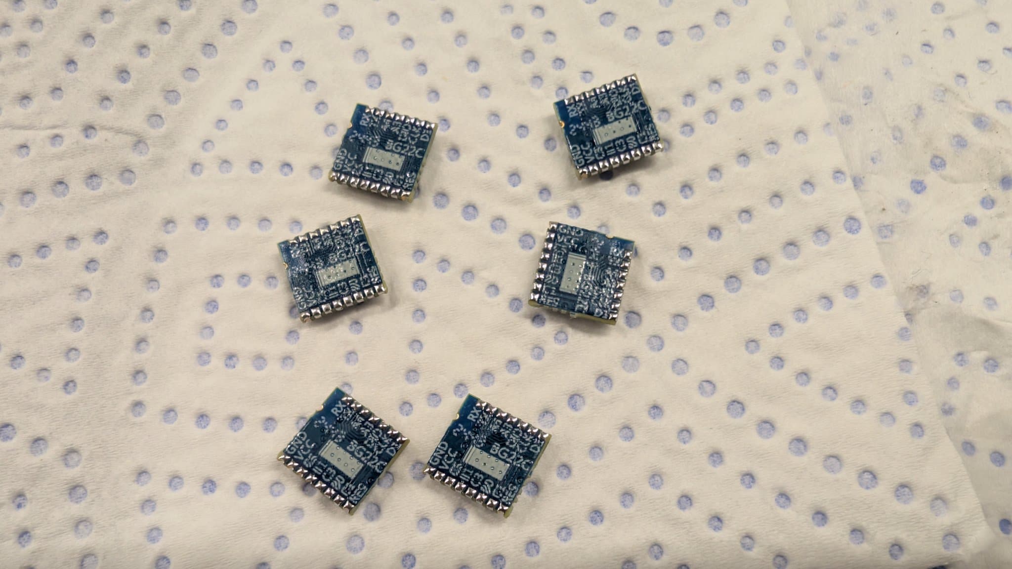 Six tinned EFR32 MCU chips arranged on dotted antistatic mat for WavePhoenix receiver assembly.
