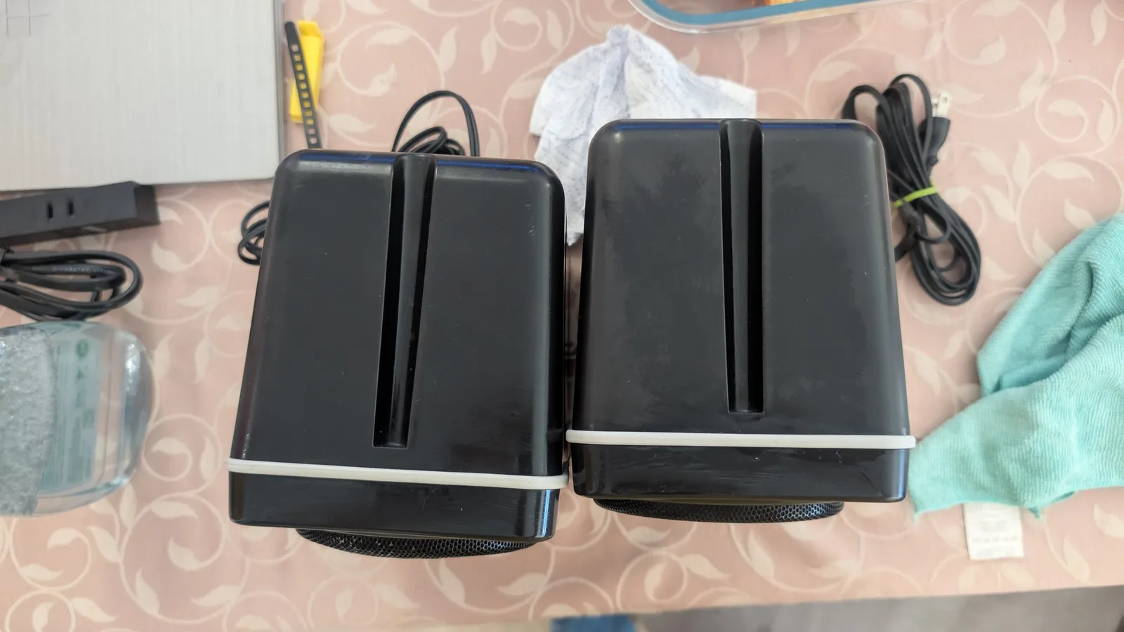 Two black BOSS MA-12AV speakers with white trim on a patterned tablecloth, still wet from the Aerospace 303 protectant application.