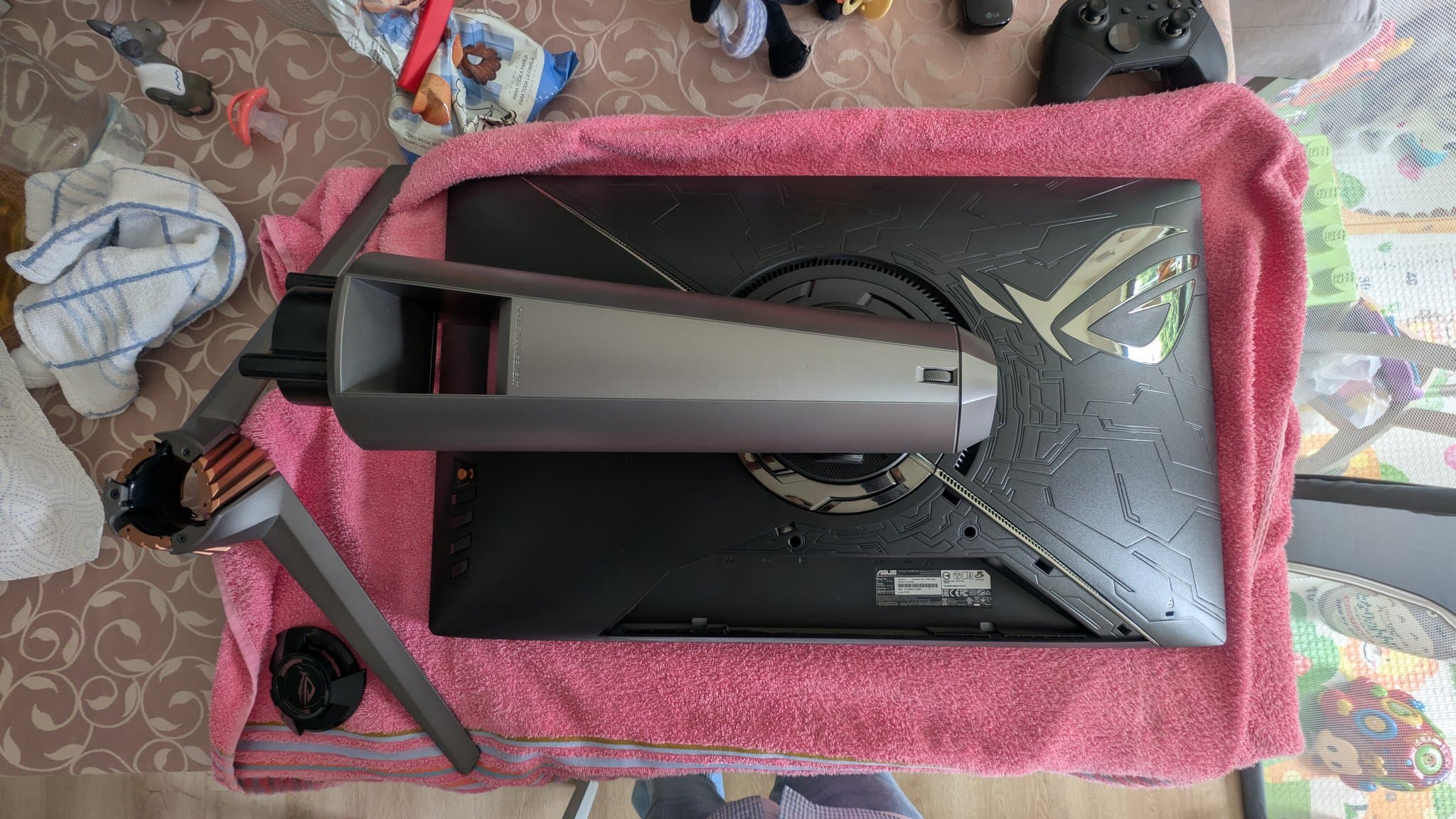 Asus PG27UQ monitor disassembled on pink towel, exposing internal fan and heatsink during refurbishment maintenance.