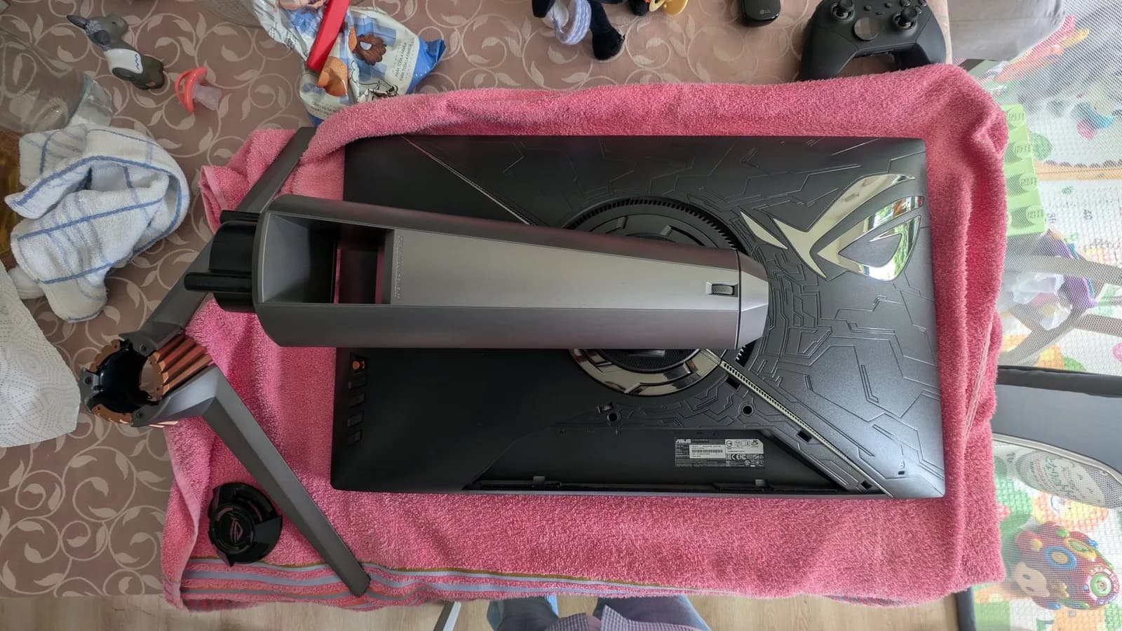 Asus PG27UQ monitor disassembled on pink towel, exposing internal fan and heatsink during refurbishment maintenance.