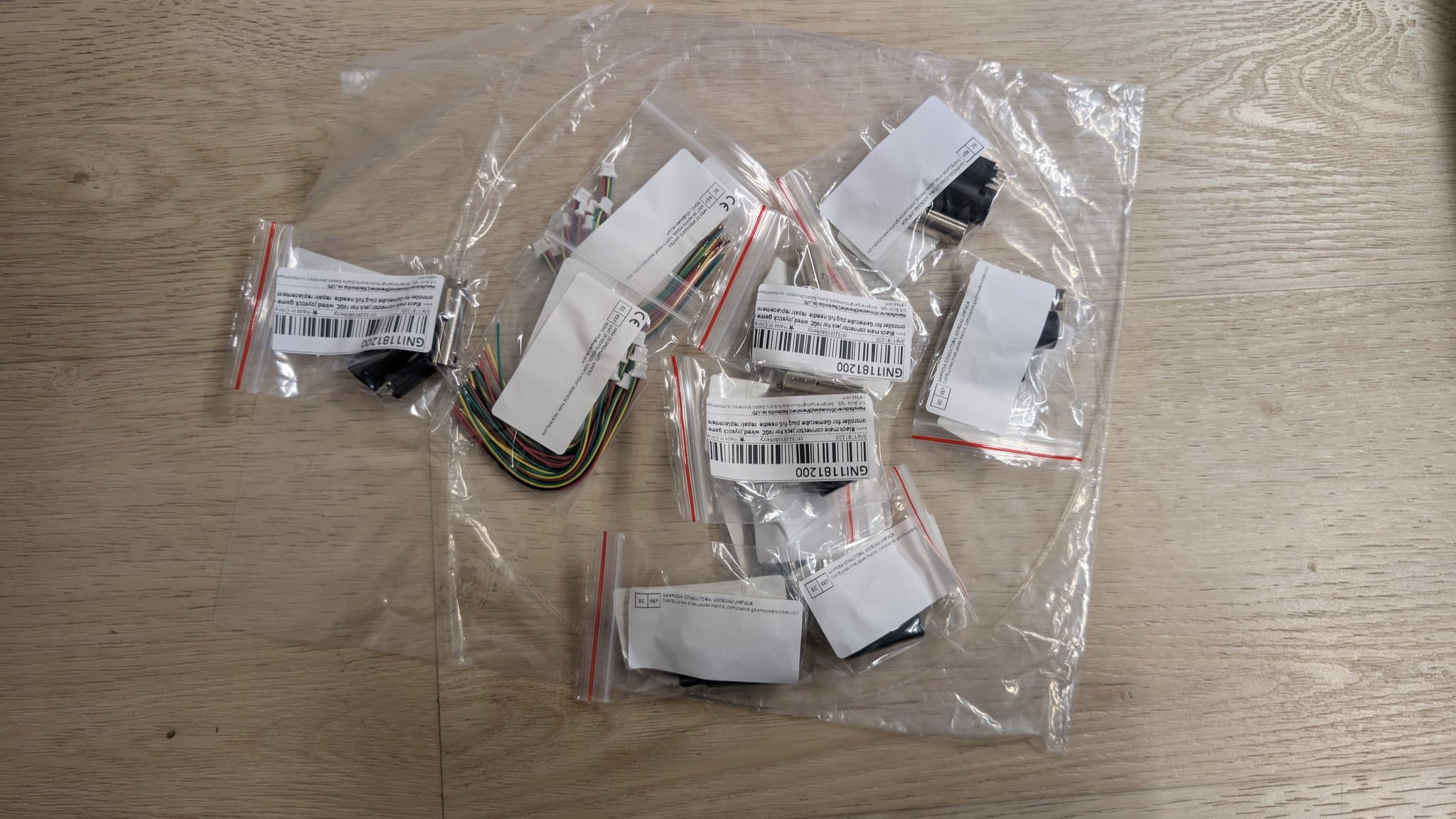 WavePhoenix WaveBird receiver PCB components and wiring in clear plastic bags with barcode labels, organized on wooden surface.