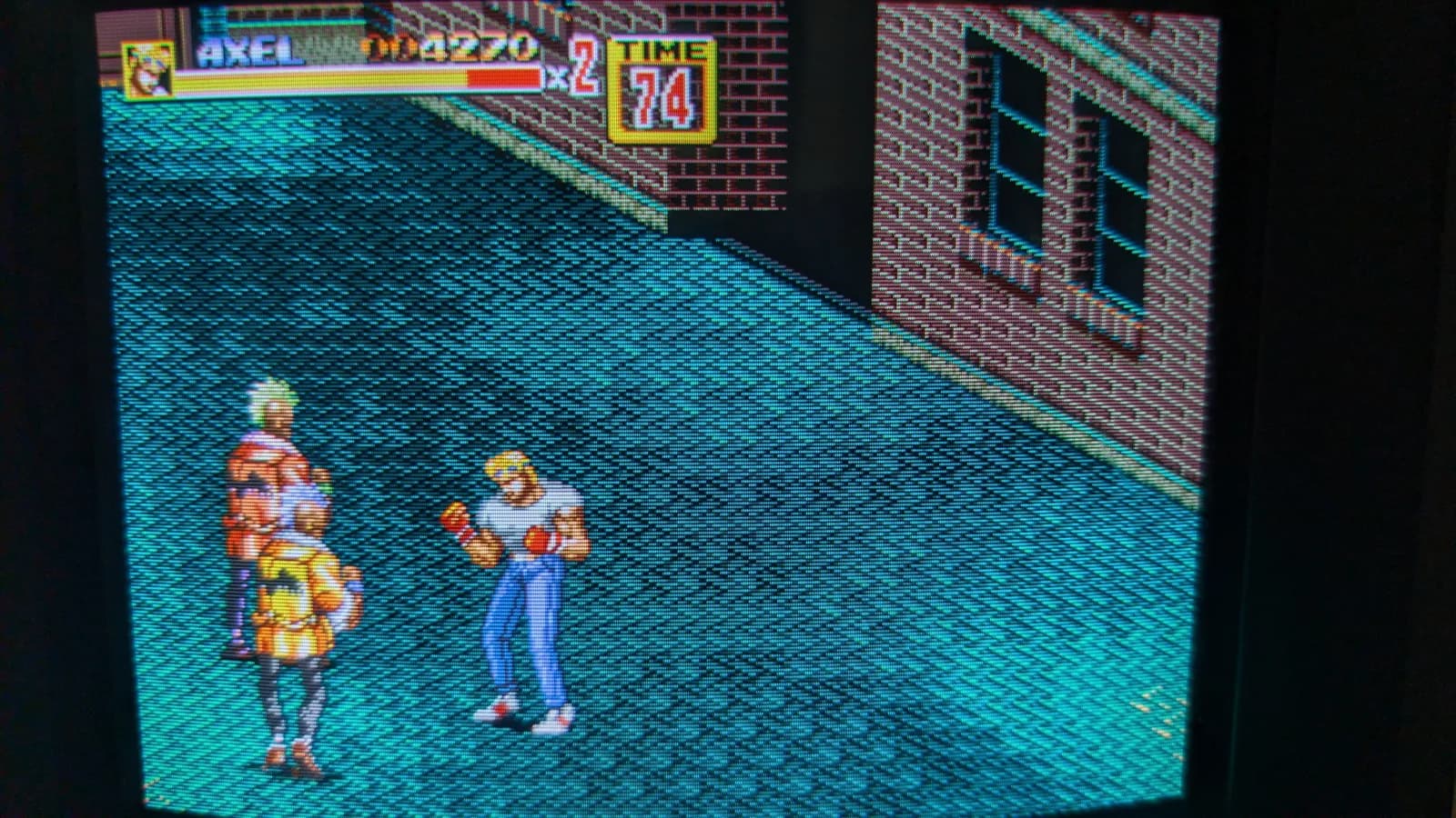 Close photo of a Sony PVM-9045Q showing Streets of Rage gameplay, Axel in a fighting stance facing two street enemies, one green-haired and one silver-haired, with the score and timer in the on-screen HUD.