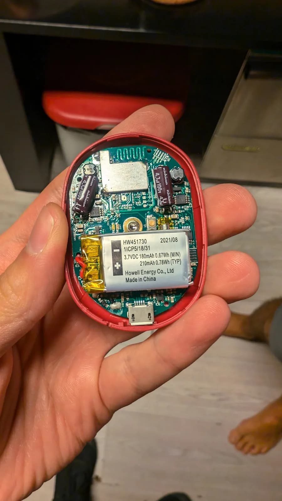 PowerDot internals in red casing showing green PCB with battery, capacitors, and USB port with all pins desoldered from board.
