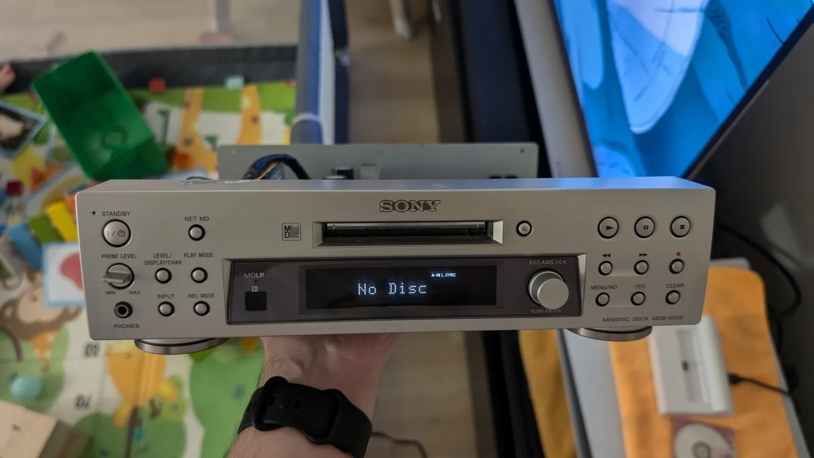 Sony MDS-S500 MiniDisc deck display showing "No Disc" error, held in hands during troubleshooting of loading mechanism issue.