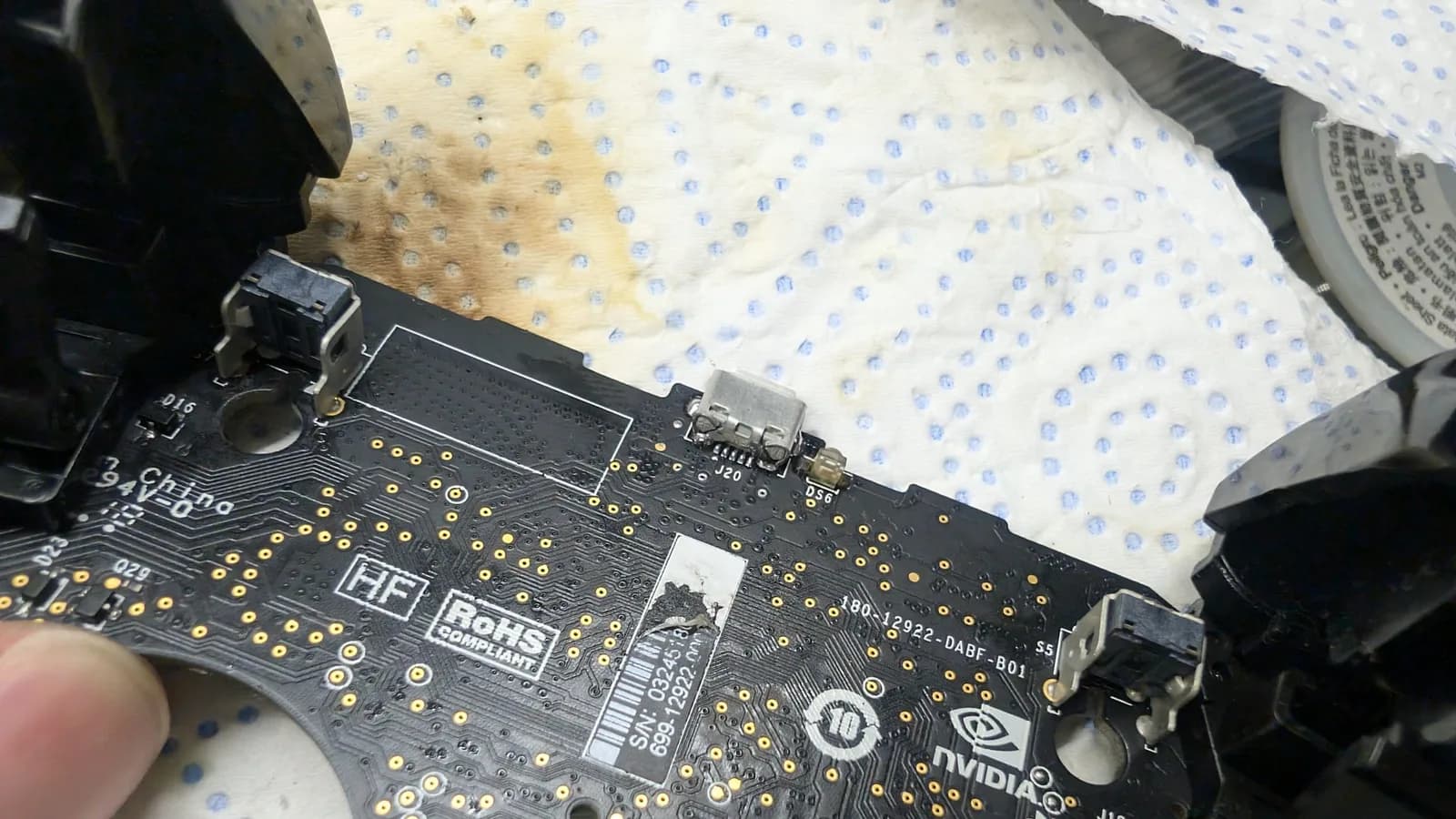 Close-up of Nvidia Shield controller PCB showing replaced USB port with gold solder pads visible, blue dotted cloth background.