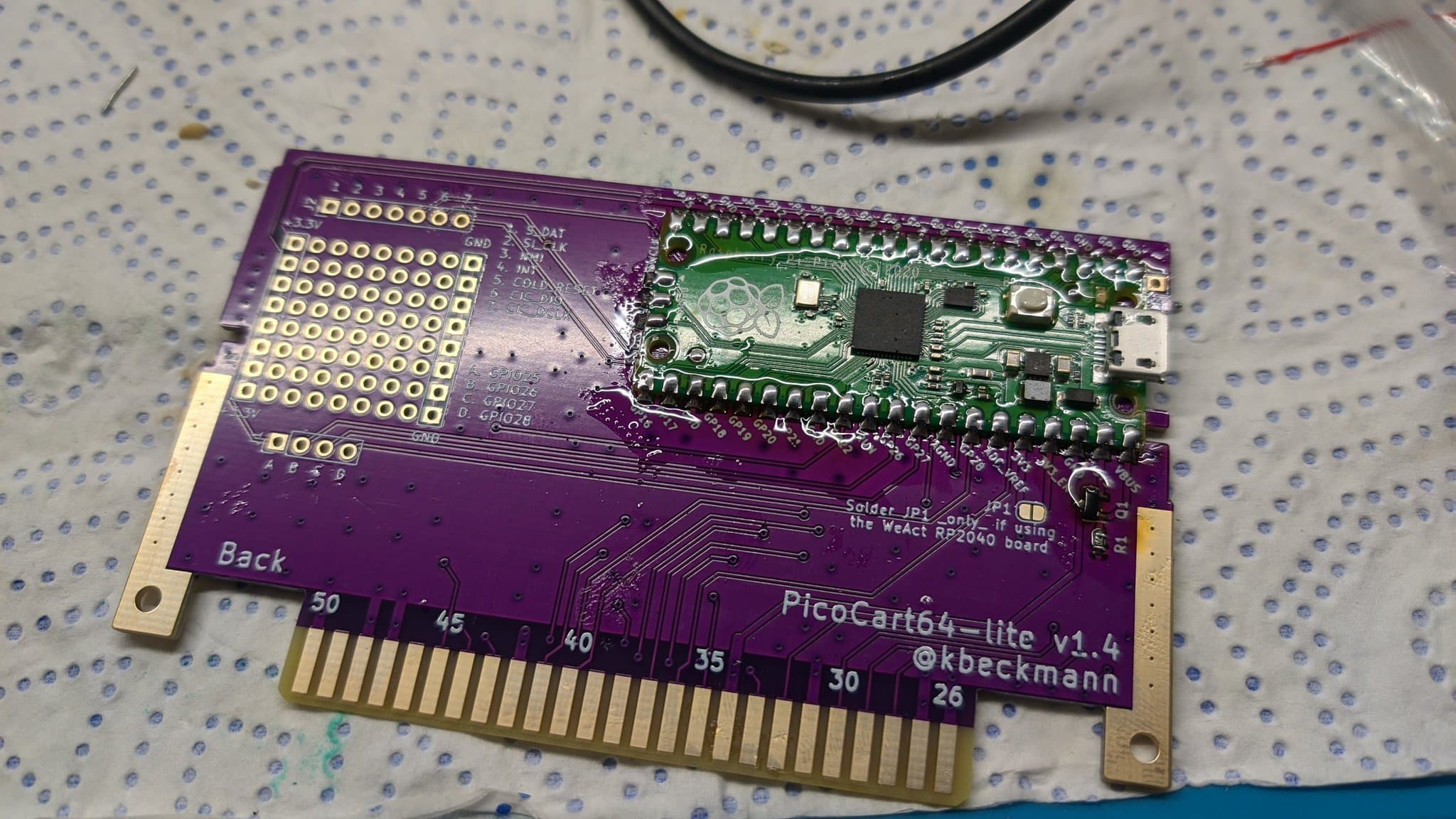 PicoCart64 lite v1.4 PCB assembly showing purple circuit board with Raspberry Pi Pico microcontroller and gold-plated N64 cartridge connector.