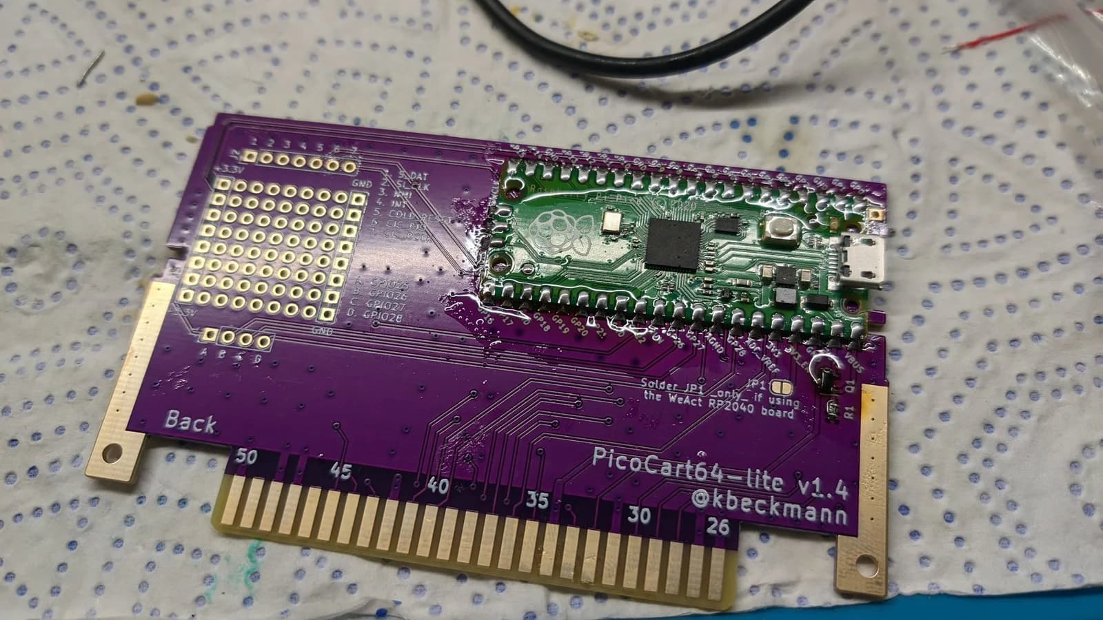 PicoCart64 lite v1.4 PCB assembly showing purple circuit board with Raspberry Pi Pico microcontroller and gold-plated N64 cartridge connector.