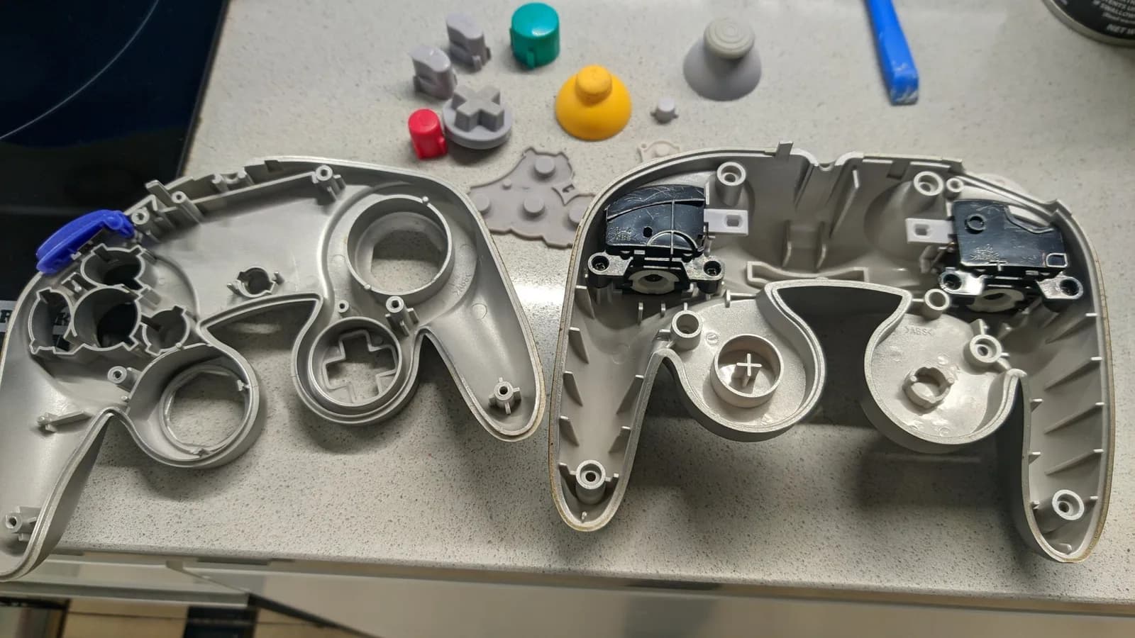 Disassembled controller shells and internal components laid out after ultrasonic cleaning, showing cleaned plastic parts and small hardware pieces.