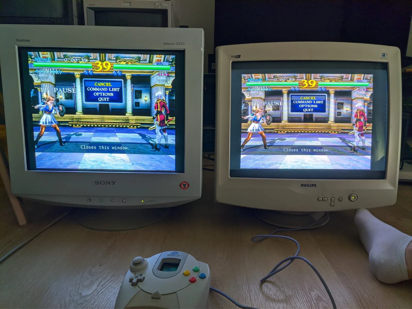 Two CRTs side by side, both fed the same Soul Calibur signal from one Dreamcast: the Sony CPD-G420 (aperture grille, left) versus the Philips 109S4 (shadow mask, right), a Dreamcast controller below.