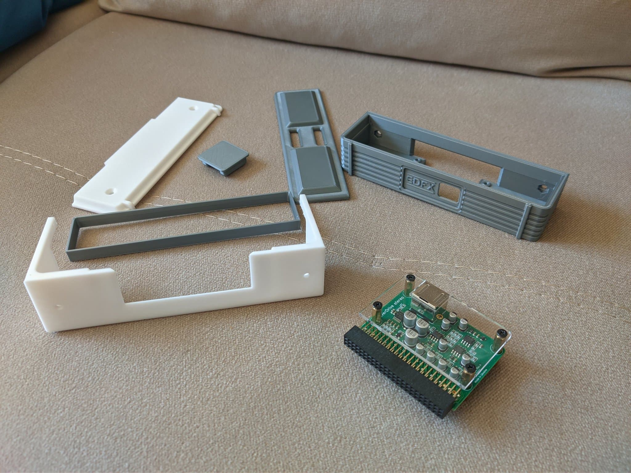 Components laid out during the refurbishment: the grey 3D-printed EDFX enclosure at right, the Krikzz EDFX itself (a small PCB with a clear acrylic panel screwed on top), alongside the SuperGrafx's white plastic shell parts, grey metal shielding and green mainboard.