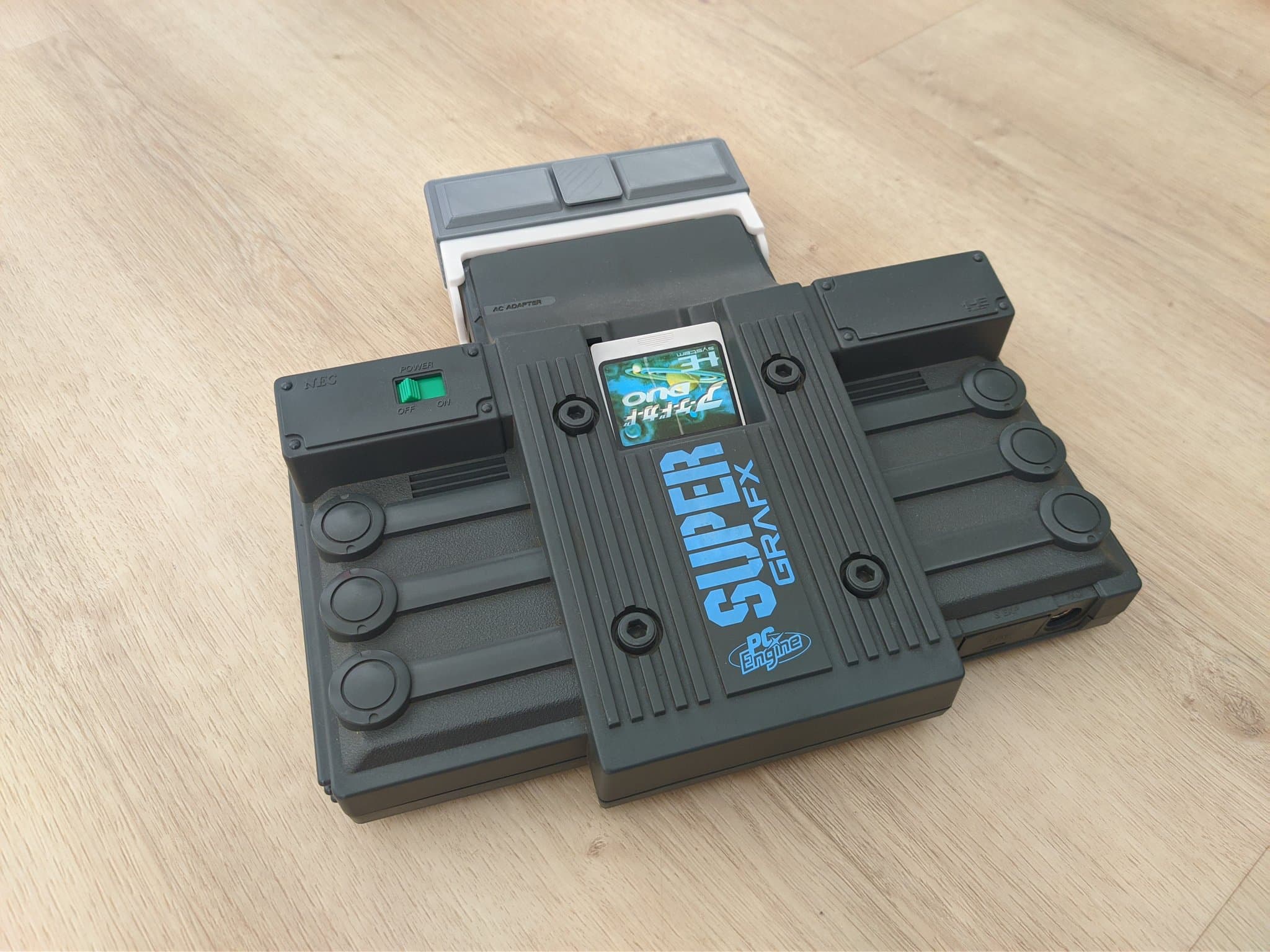 Refurbished NEC PC Engine SuperGrafx on a wooden surface, with the Krikzz EDFX A/V adapter in its 3D-printed mini-IFU shell and an Arcade Card Duo seated in the HuCard slot.