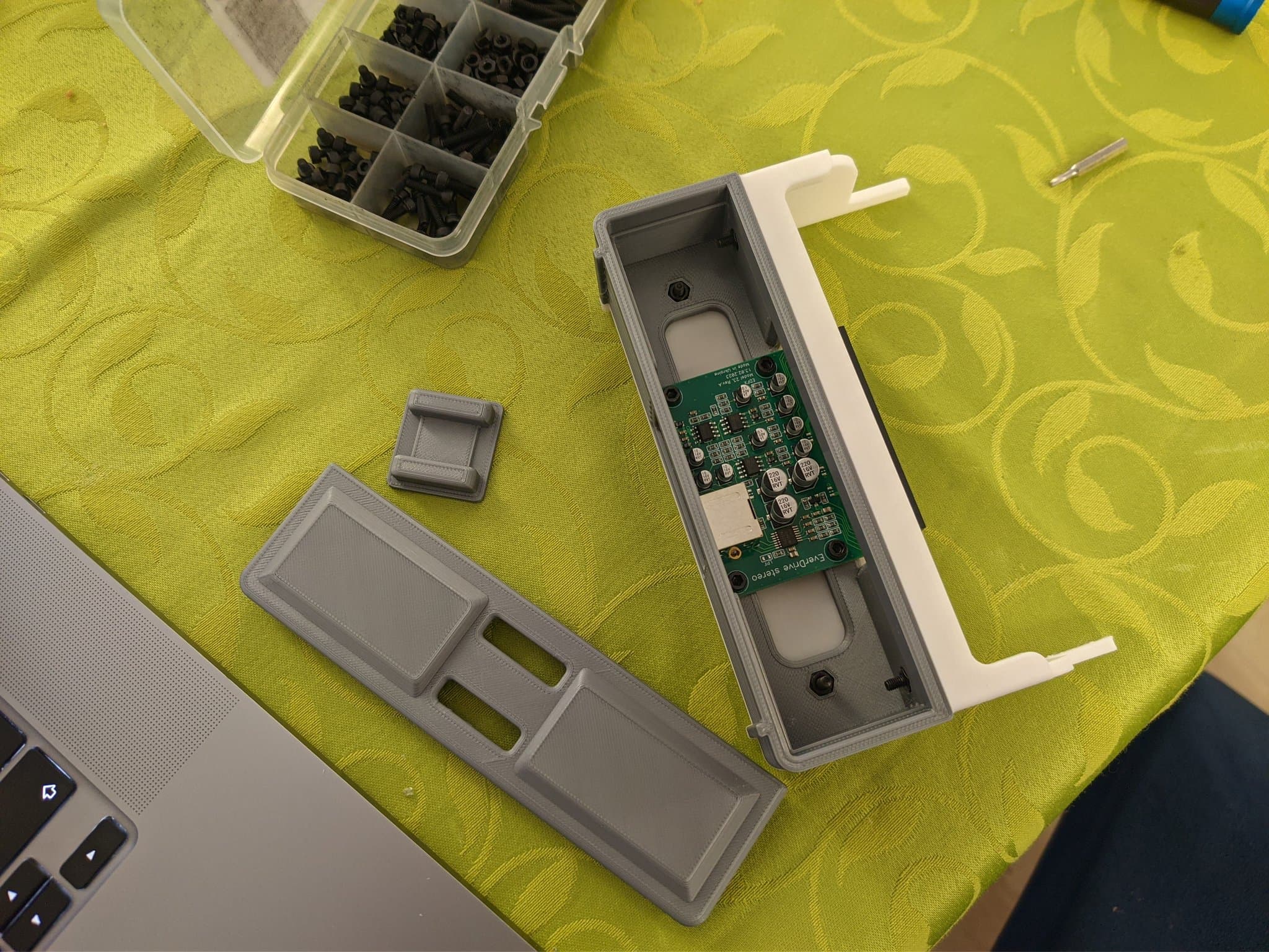 The Krikzz EDFX PCB being installed into its 3D-printed mini-IFU housing, with the housing parts and a hardware organizer of screws on the workbench.