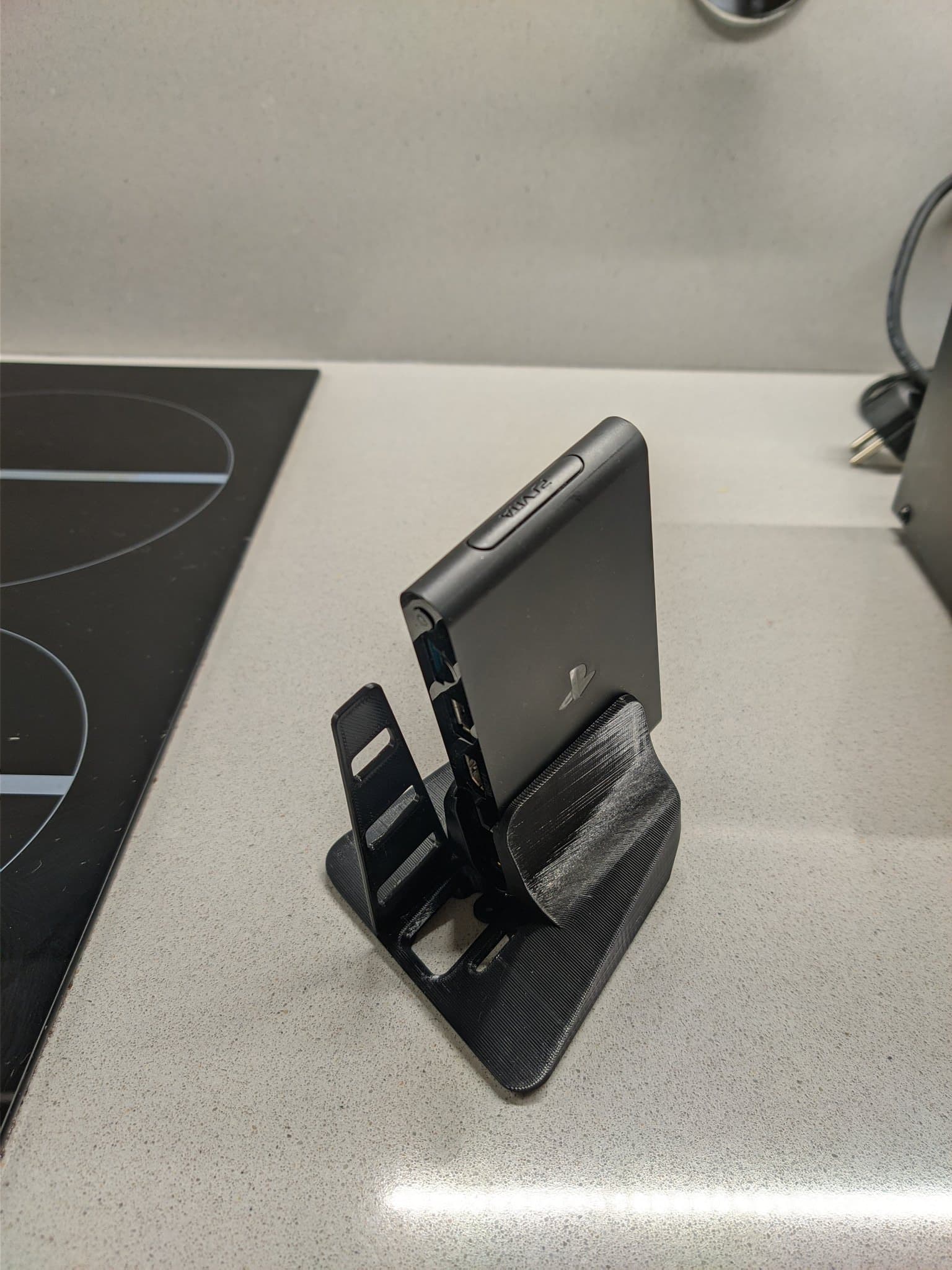 Sony PS Vita TV mounted on black Jeff Chen stand on workbench, showing restored unit after cleaning and CFW installation.