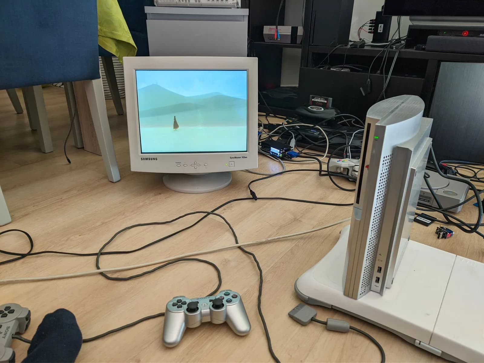 Samsung SyncMaster 763MB CRT displaying Journey, run from the silver Metal Gear Solid 4 edition PlayStation 3 sitting on a white Wii Balance Board via the gold Jeff Chen dongle, with a silver PS3 controller on the wooden floor.
