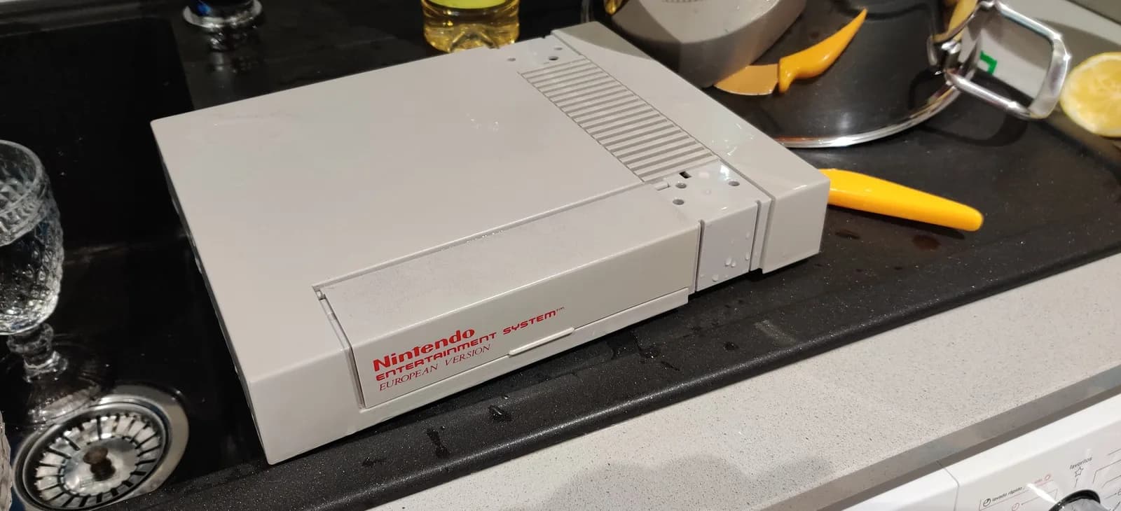 Nintendo Entertainment System European version on black desk surface surrounded by retrobriting supplies and tools.
