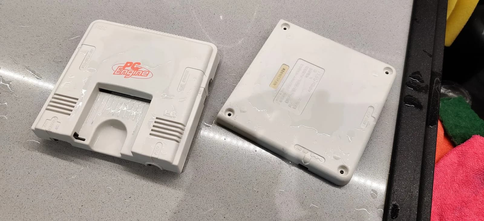 Two white PC Engine console shells displayed front and back after retrobriting treatment, showing restored plastic surfaces.