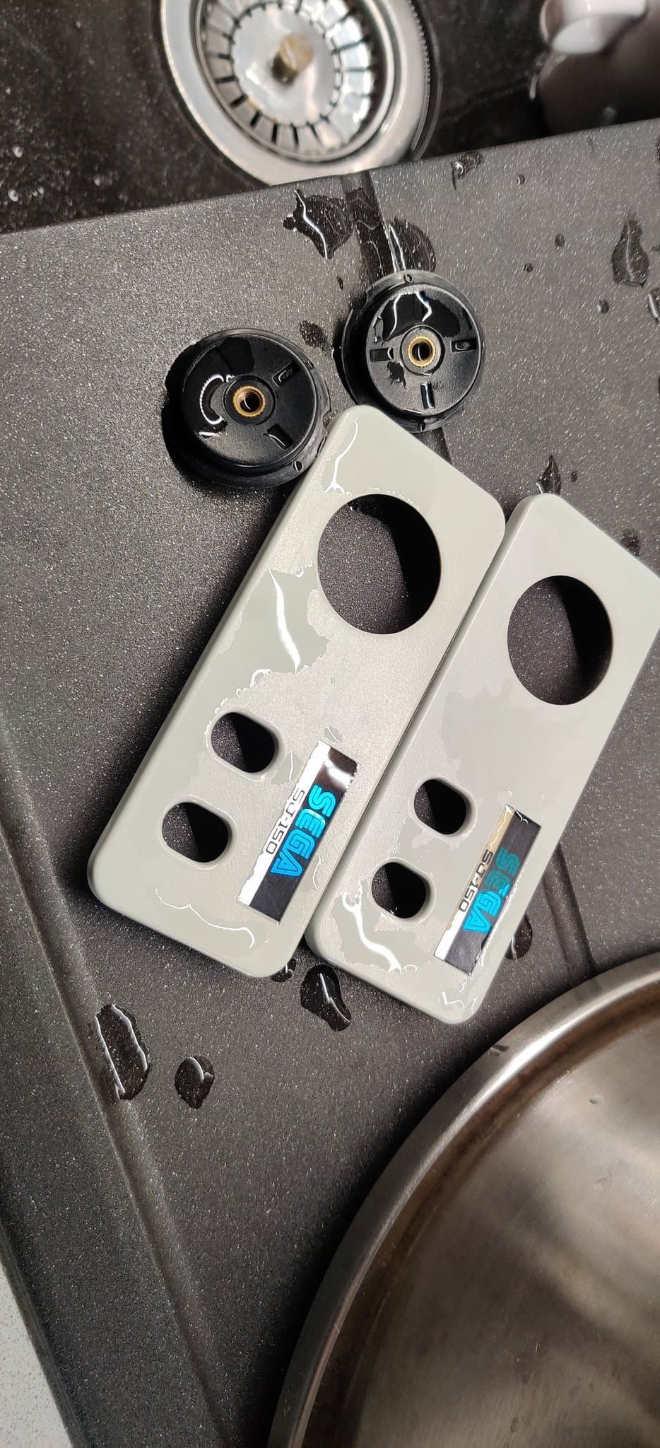 Disassembled Sega SG-1000 II controller parts showing retrobrighted white plastic shells with brass inserts and black internal components during restoration process.