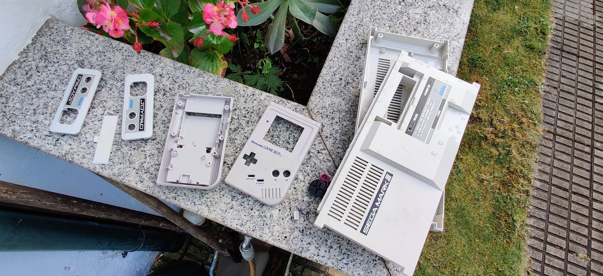 Disassembled Nintendo Game Boy DMG showing retrobrighted plastic shell components and internal parts laid out on concrete surface.