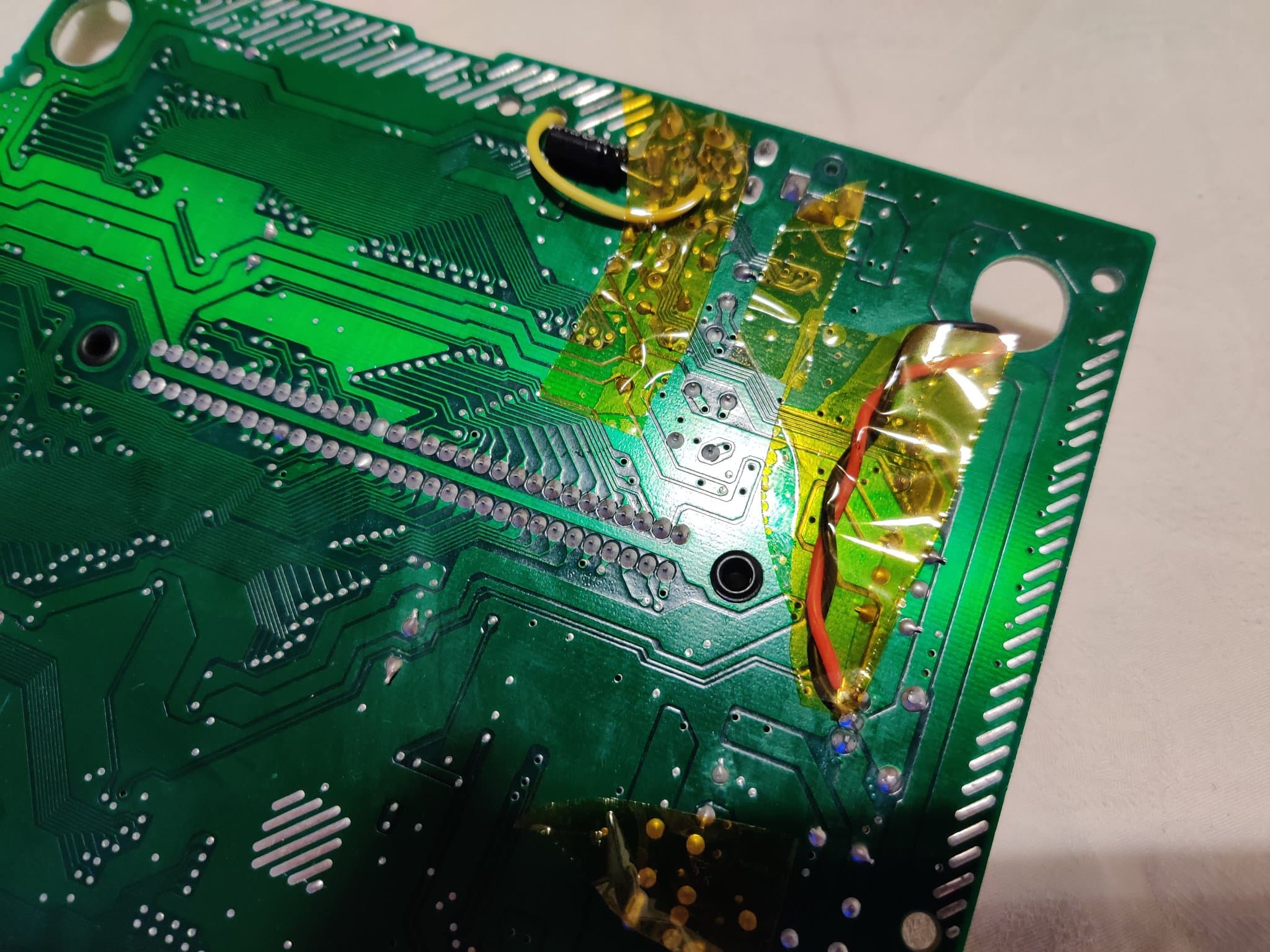 Close-up of Mega Drive RGB bypass mod installation showing soldered connections, yellow capacitors, red/black wires, and circuit board traces with slight picture oscillation noted.