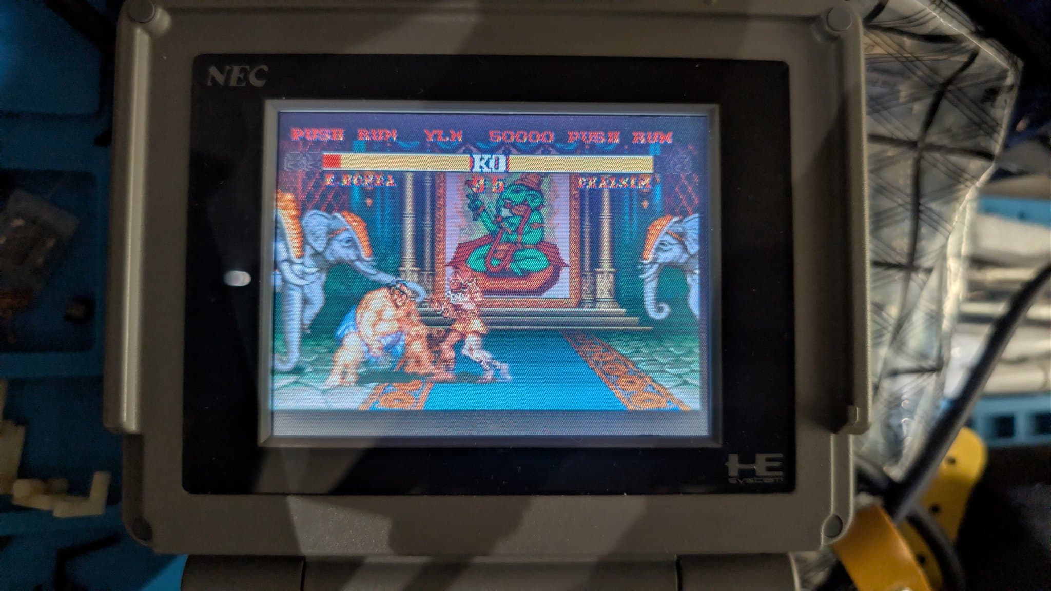 Close-up of the NEC PC Engine LT LCD showing Street Fighter II gameplay in the temple stage early in a round, both health bars near full with 95 seconds on the timer, the panel working after the repair.