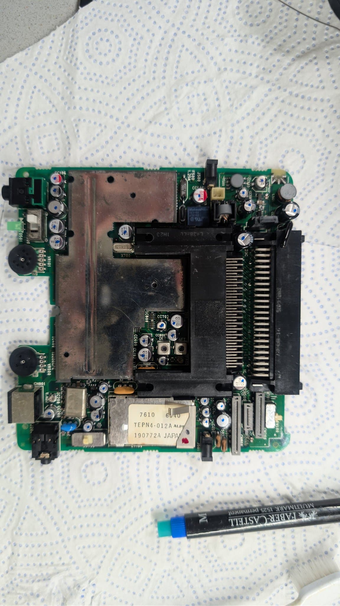 Recapped PC Engine LT mainboard with fresh electrolytic capacitors installed, the HuCard slot and metal-can module visible, just after completing the recap.