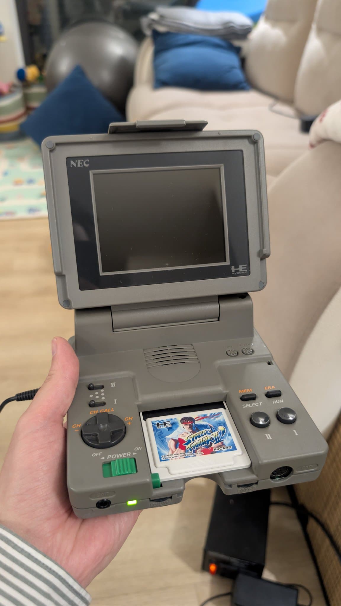 Fully assembled NEC PC Engine LT powered on with a Street Fighter II HuCard inserted: the power LED is lit but the screen shows no picture (the failed T500 and missing LCD bias voltage) and there is no sound.