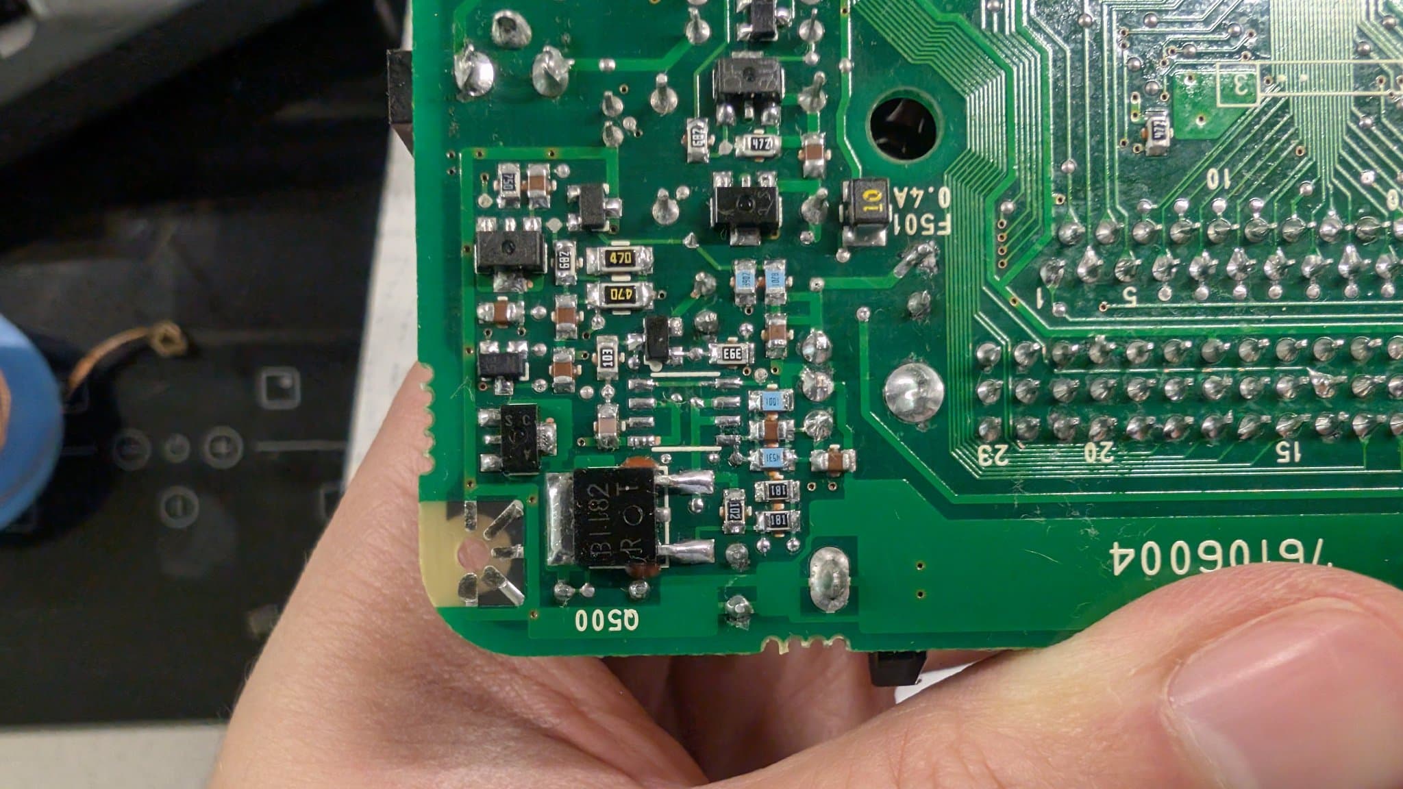 Close-up of the PC Engine LT board held in hand at the 6.5V regulator (M5291FP) area, the M5291FP lifted out of its footprint to check for damage beneath it, with the Q500 position and surrounding SMD parts visible during the repair.