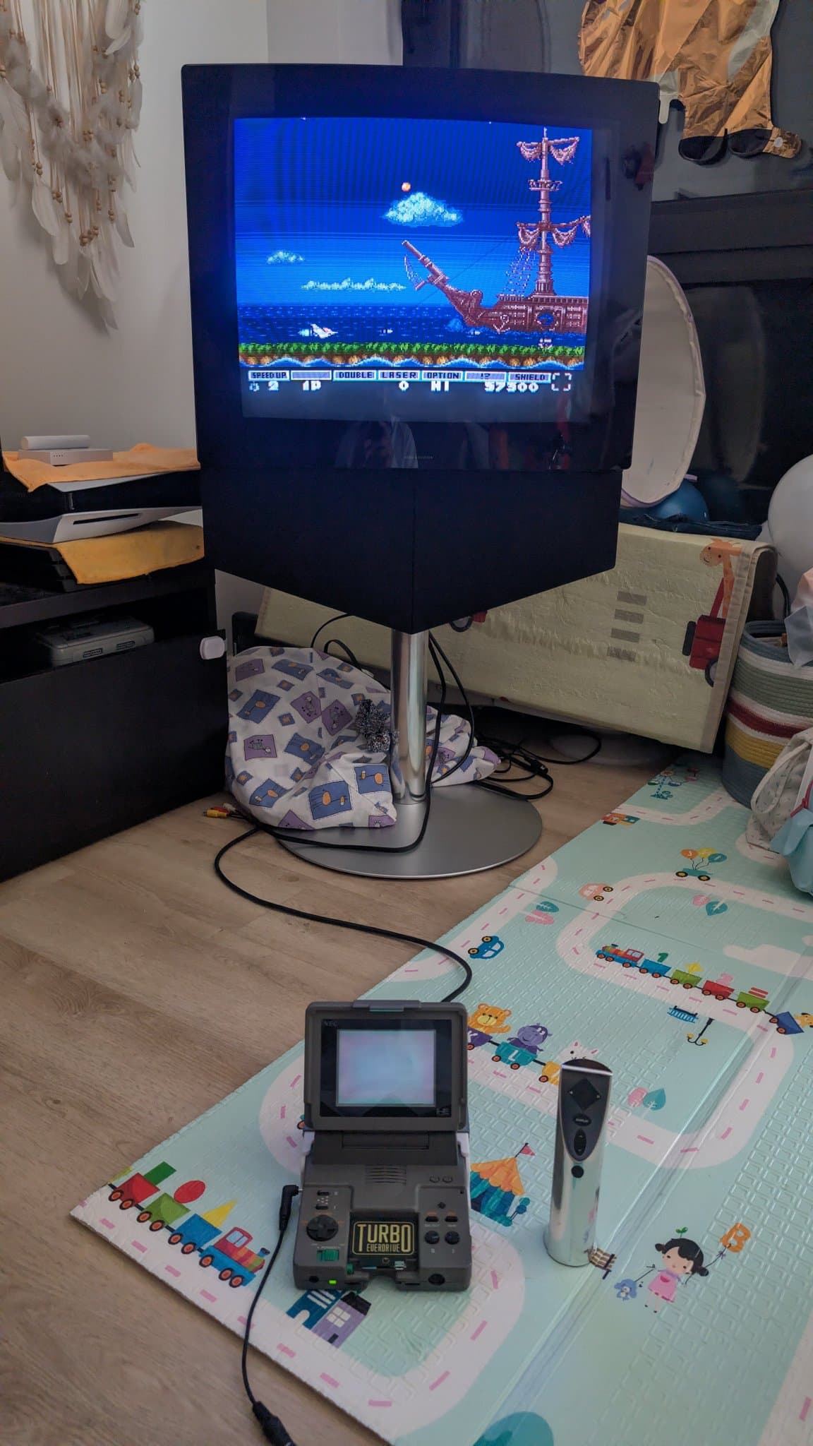 NEC PC Engine LT, working, displaying Parodius Da! from a Turbo EverDrive Pro flashcart on a Bang & Olufsen Beovision 1 CRT, with RGB tapped from the LT's Ext Bus (expansion) port by a Krikzz EDFX adapter and carried over a Mega Drive 2 RGB cable, a controller on the play mat.