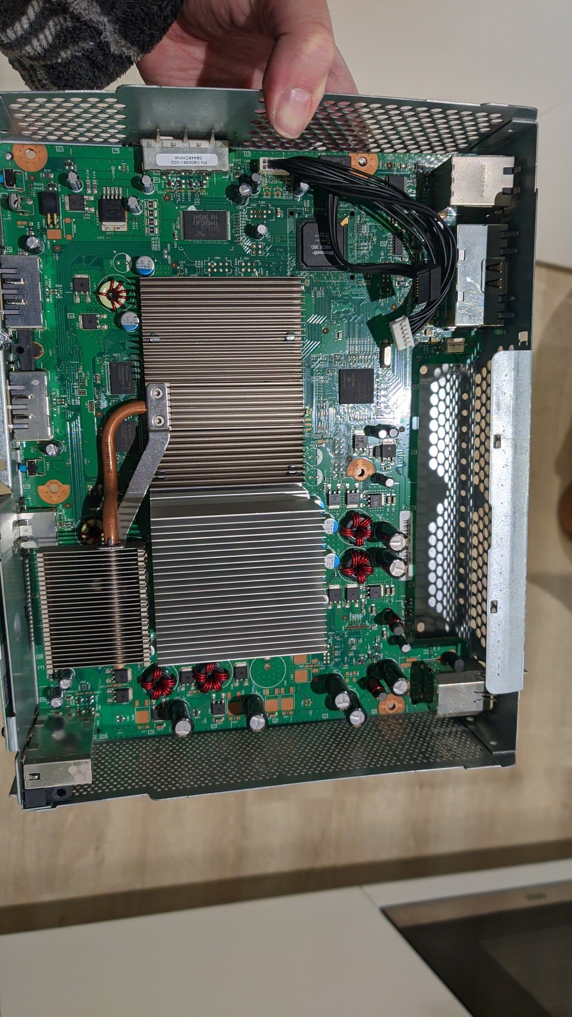 Xbox 360 motherboard with large heatsink removed, exposing GPU and power delivery components during laser drive repair.