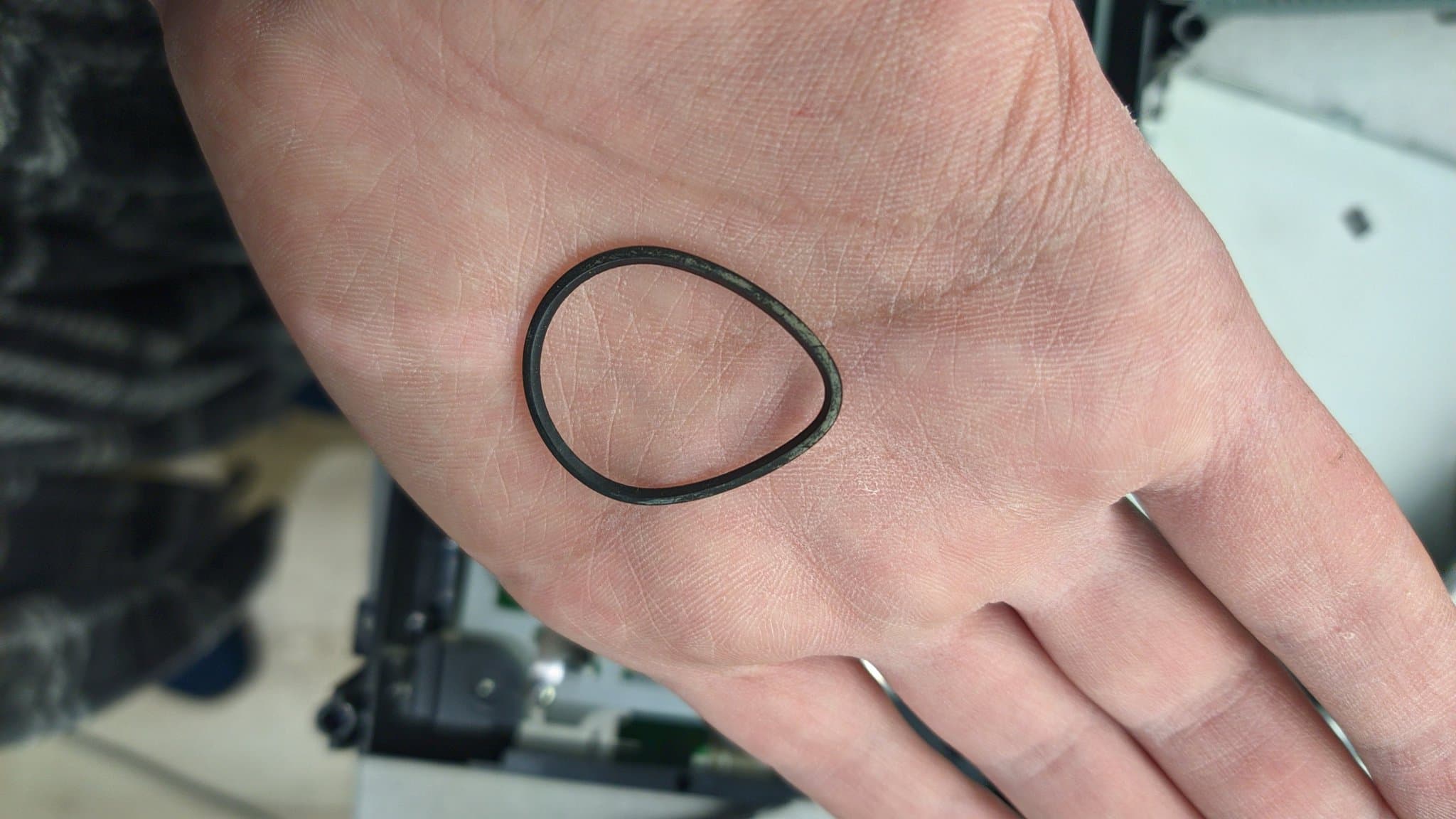 Close-up of a hand showing a simple black oval outline drawn on the palm, likely indicating laser lens location or replacement point on Xbox 360 drive.