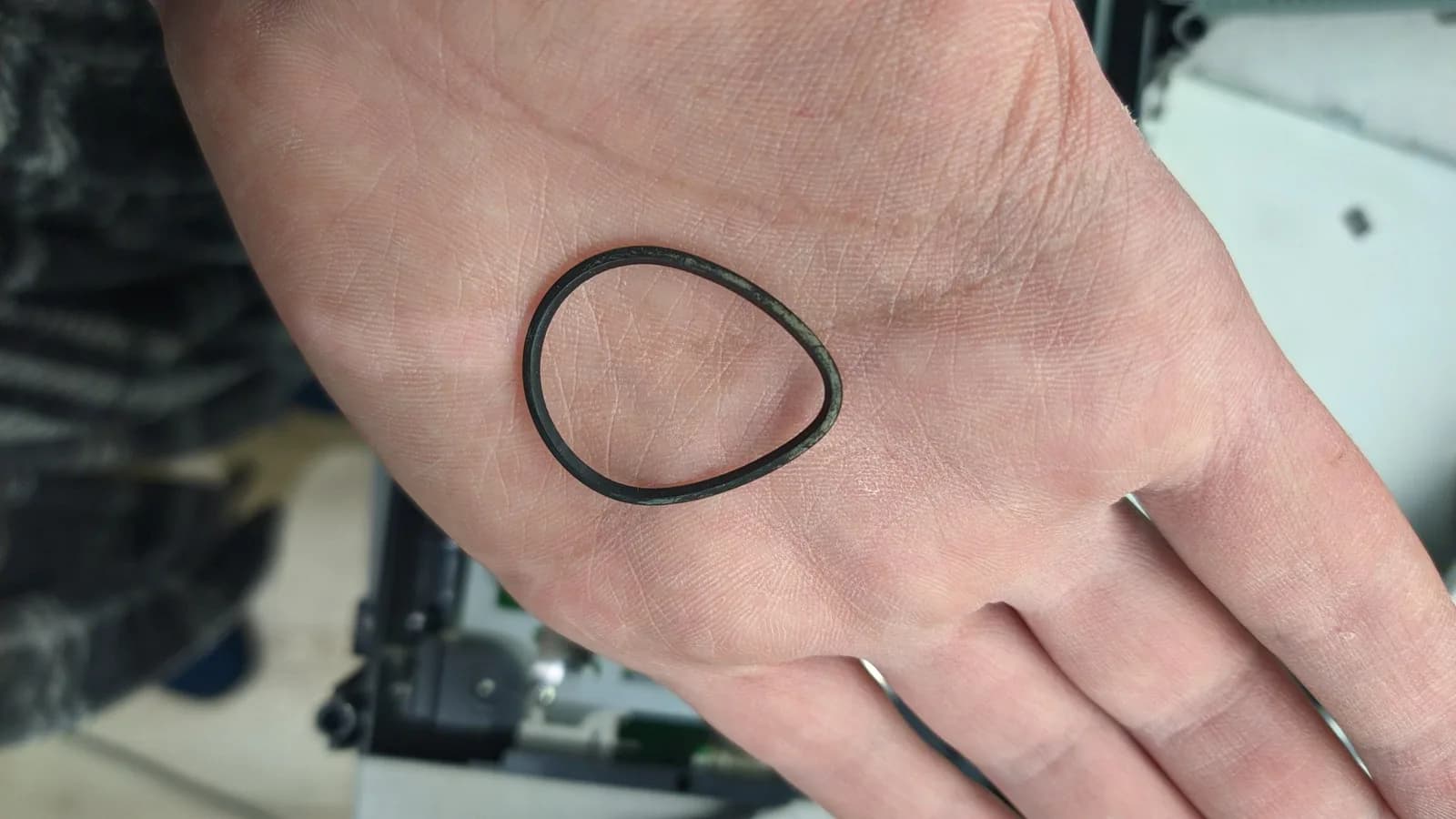 The Xbox 360 optical drive tray's belt, oval and grimy with age, before being boiled to restore its shape and cleaned.