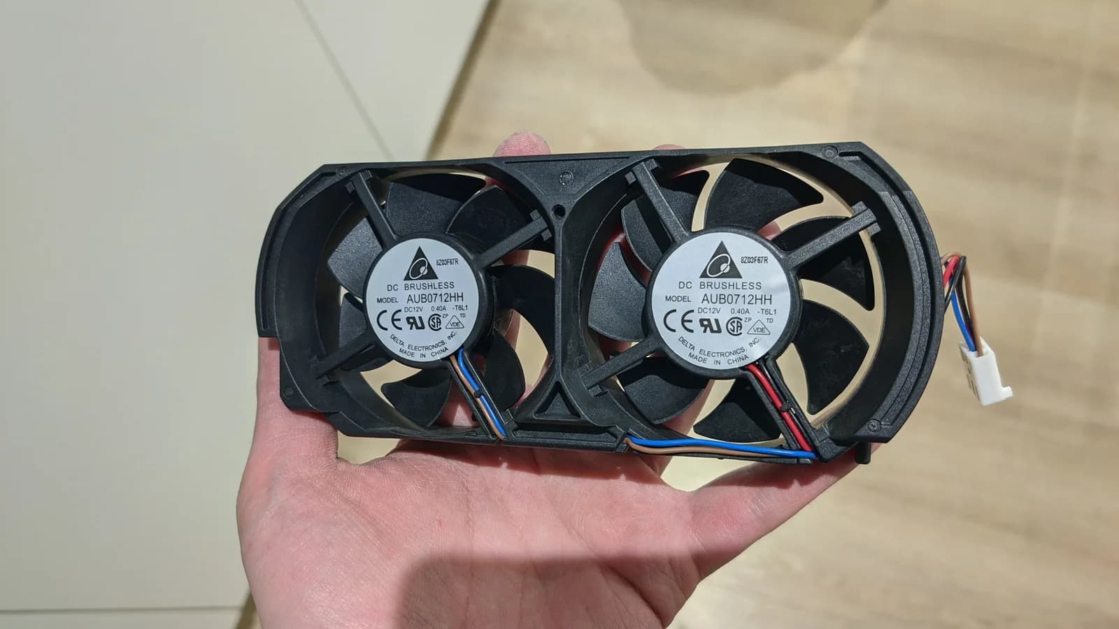 Two Xbox 360 cooling fans held in the palm, their wires visible, removed during the dust cleanup.