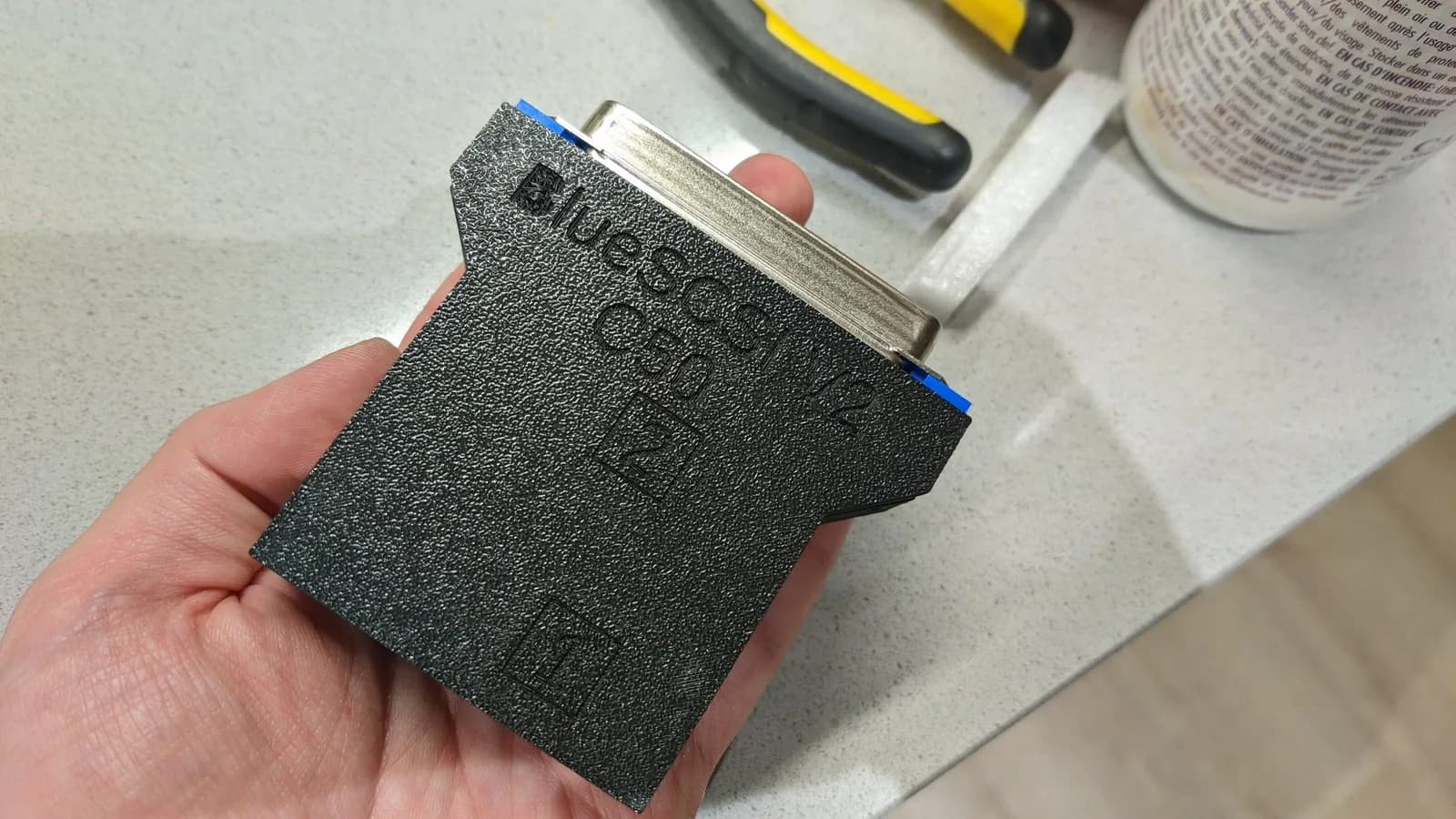 The assembled BlueSCSI v2 held in hand in its thin plastic shell, the one that is brittle and not recommended.