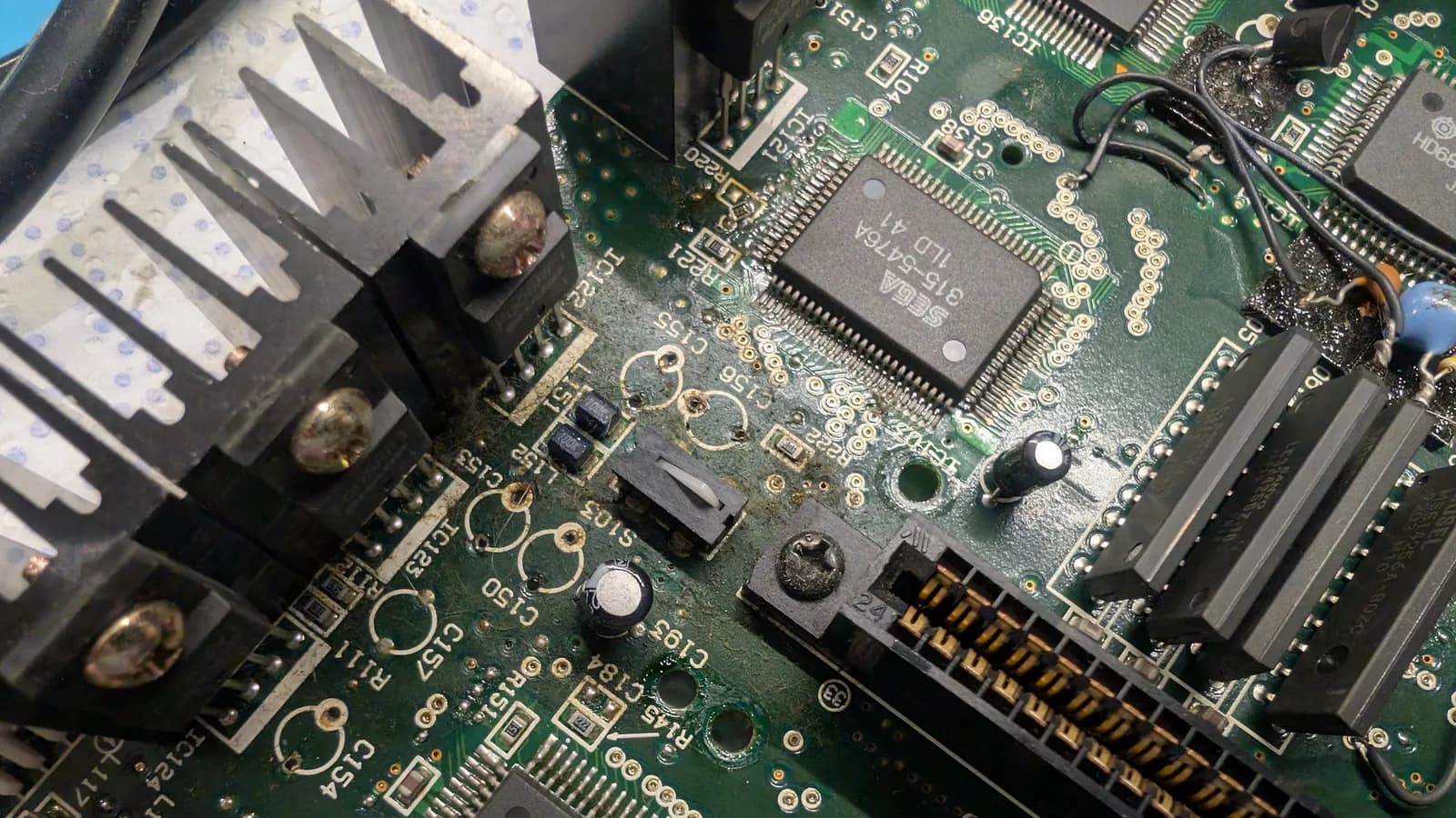 Victor RG-M1 motherboard during recap with visible capacitor leakage near voltage regulators and fresh solder joints from board restoration work.
