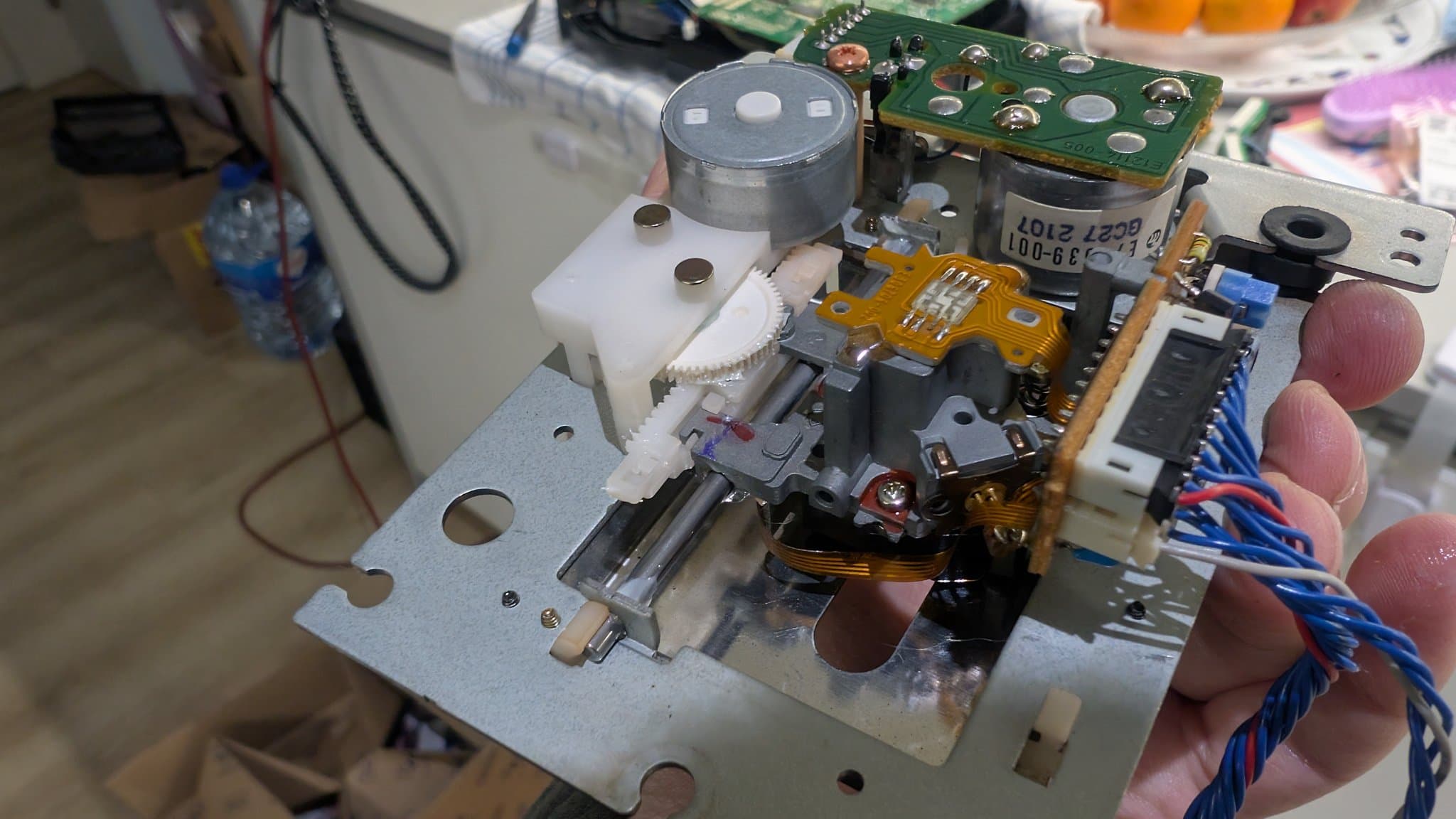 Wondermega audio/karaoke effects and laser board after recap, showing green PCB, capacitors, yellow flex ribbon, and cleaned laser sled components held in hand.