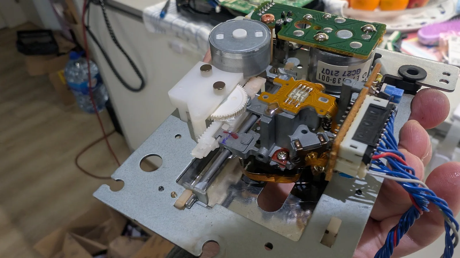 Wondermega audio/karaoke effects and laser board after recap, showing green PCB, capacitors, yellow flex ribbon, and cleaned laser sled components held in hand.