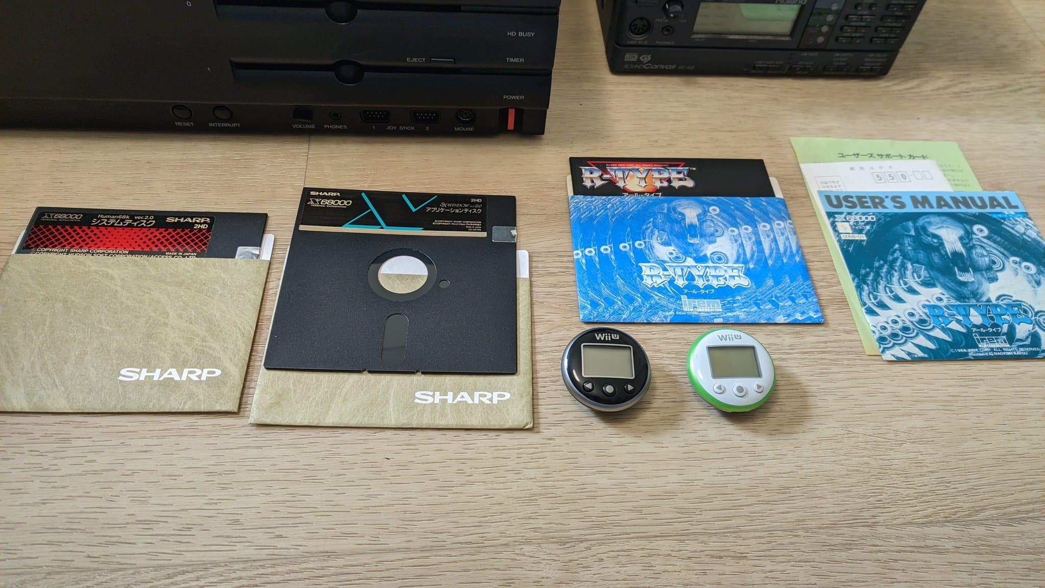 The Sharp X68000 Pro II on the floor, surrounded by floppy disks, software, the Roland MIDI modules and two Wii U pedometers.