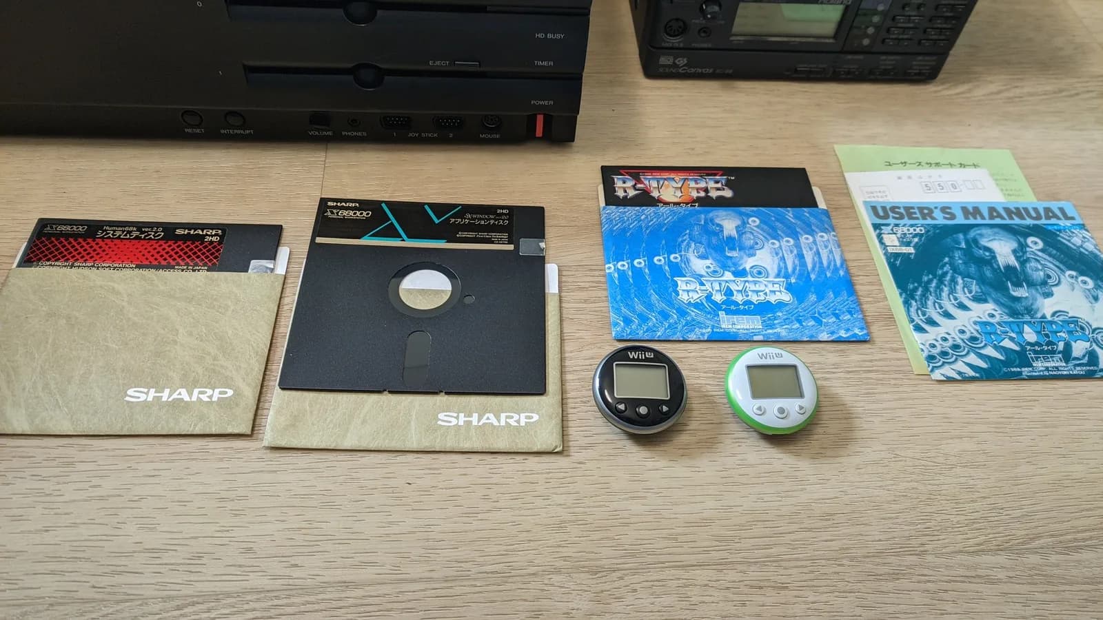 The Sharp X68000 Pro II on the floor, surrounded by floppy disks, software, the Roland MIDI modules and two Wii U pedometers.