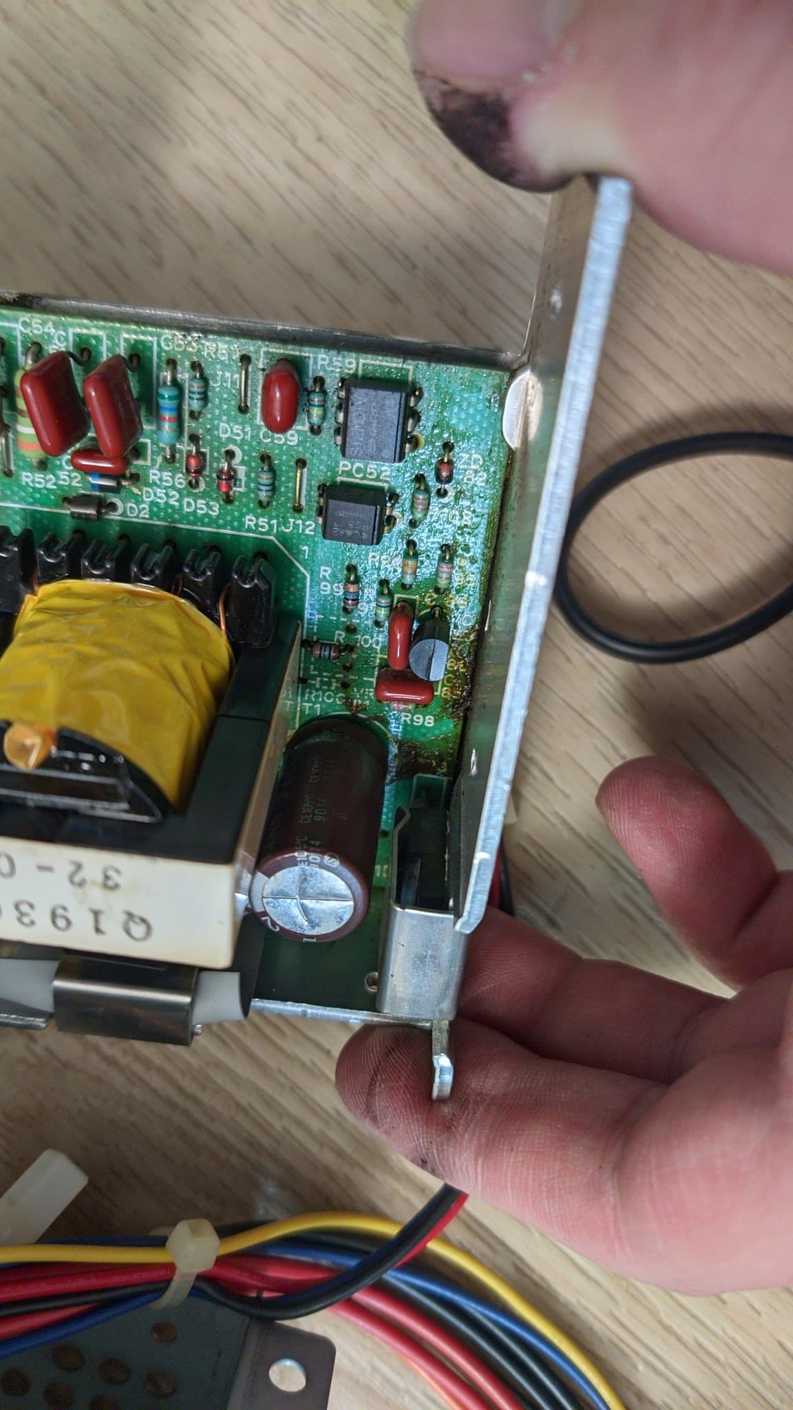 Close-up of the Sharp X68000 Pro II power supply board with a failed electrolytic capacitor beside the transformer, the PSU's own wires alongside, the likely reason it would not power on.
