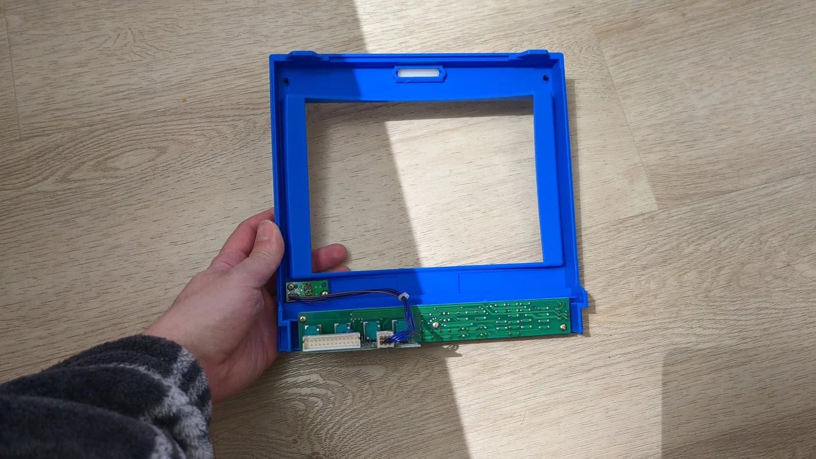 Disassembled blue plastic bezel frame of Ikegami HTM-1005RA2 monitor showing internal PCB with connectors and components intact.
